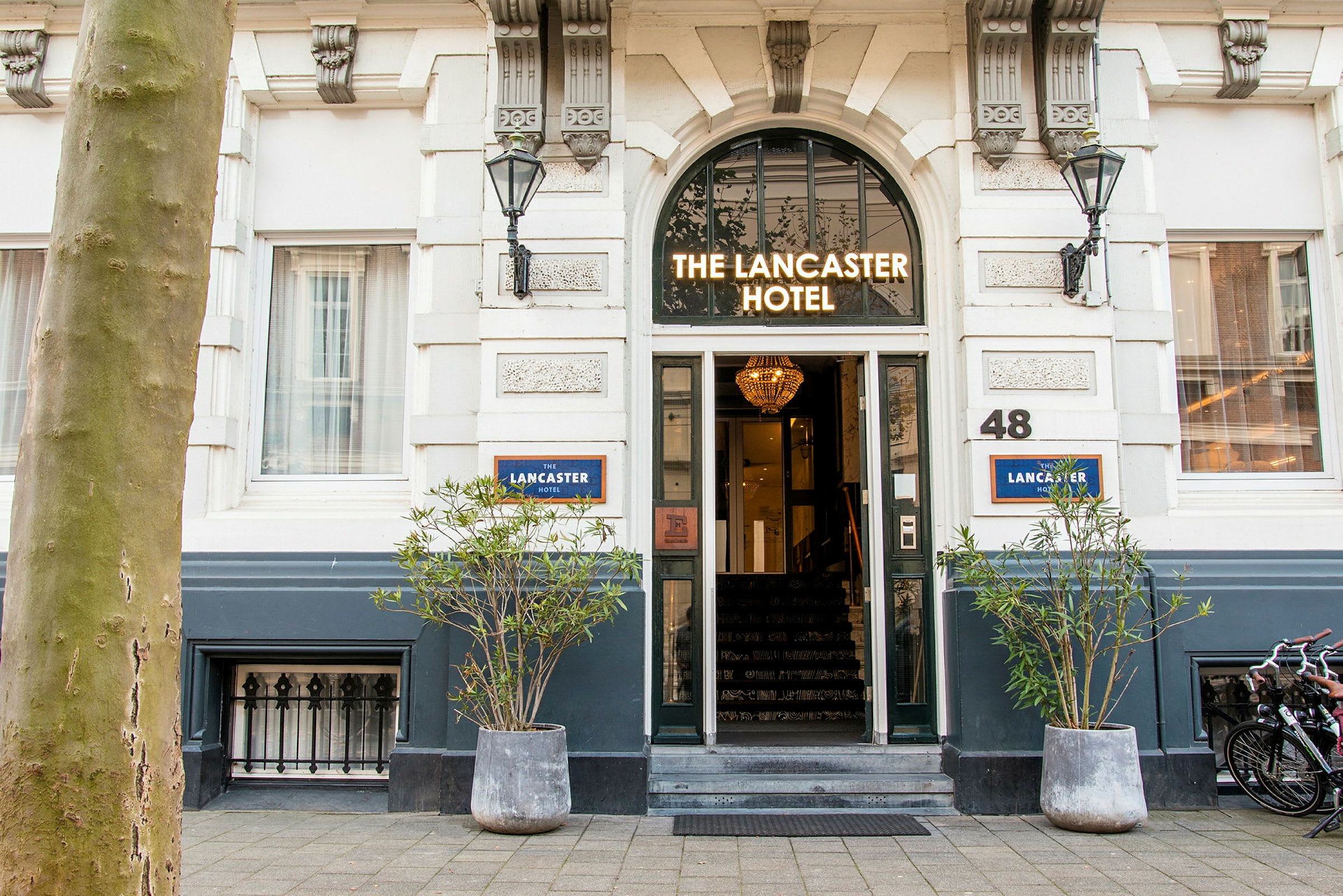Indgang til et hotel med skiltet 'The Lancaster Hotel' over døren. (AI-genereret tekst)