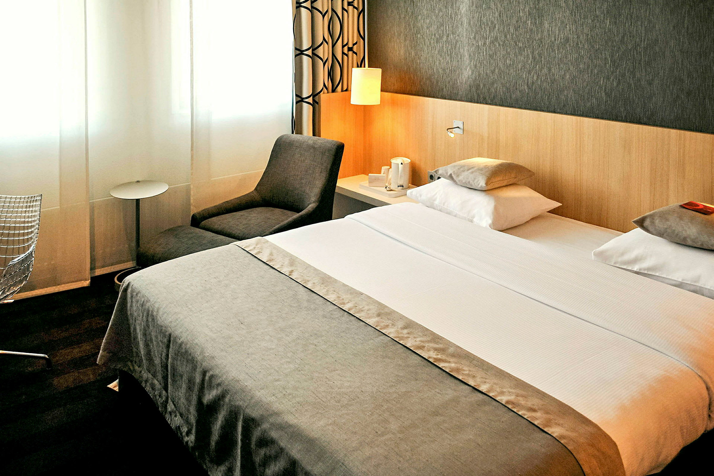Hotelværelse med dobbeltseng, lænestol og sidebord. (AI-genereret tekst)