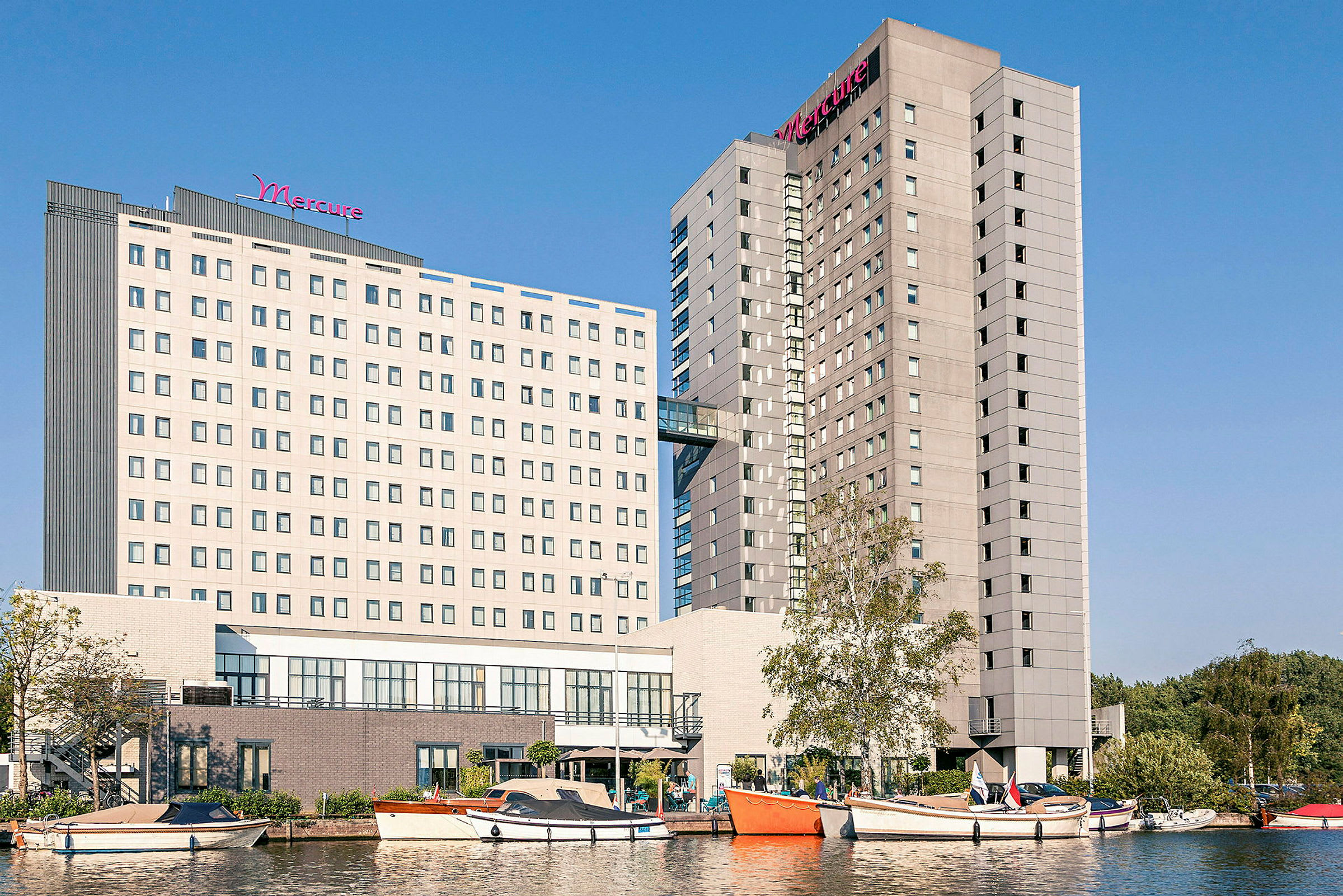 Billede af hotelbygninger med både og vand i forgrunden. (AI-genereret tekst)