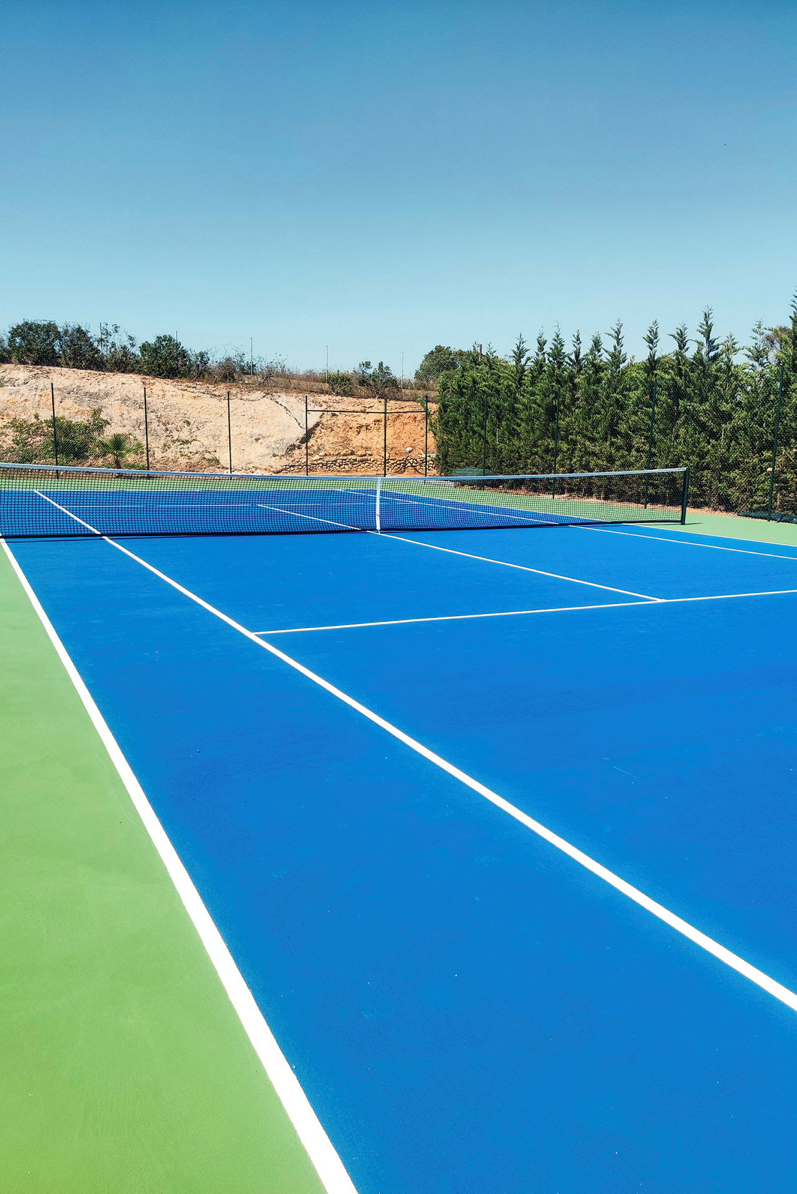 Billede af en tennisbane med blå belægning. (AI-genereret tekst)