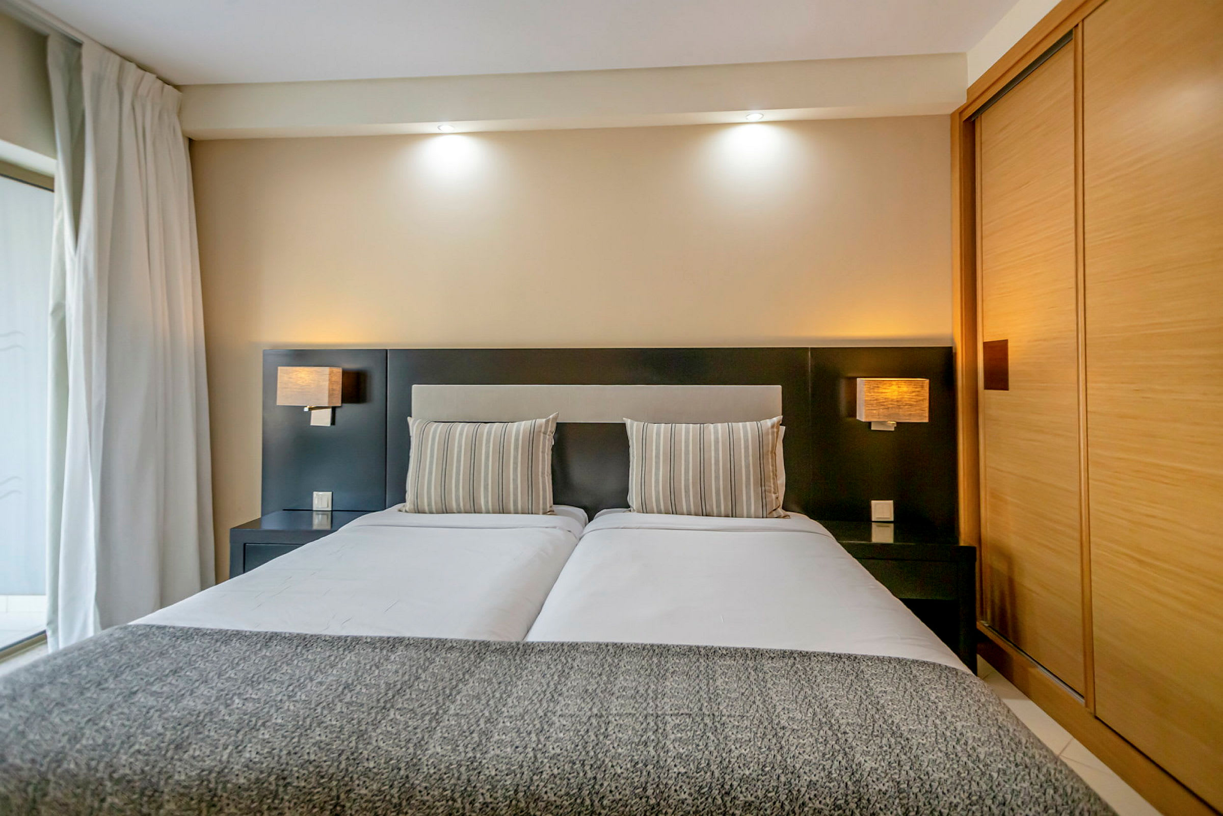 Billede af et moderne hotelværelse med en dobbeltseng, stribede puder og stilren indretning. (AI-genereret tekst)