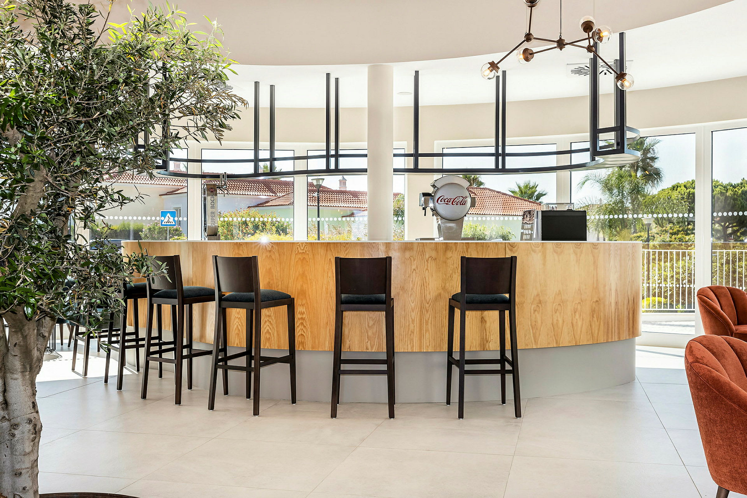 En moderne bar med høje stole og store vinduer. (AI-genereret tekst)