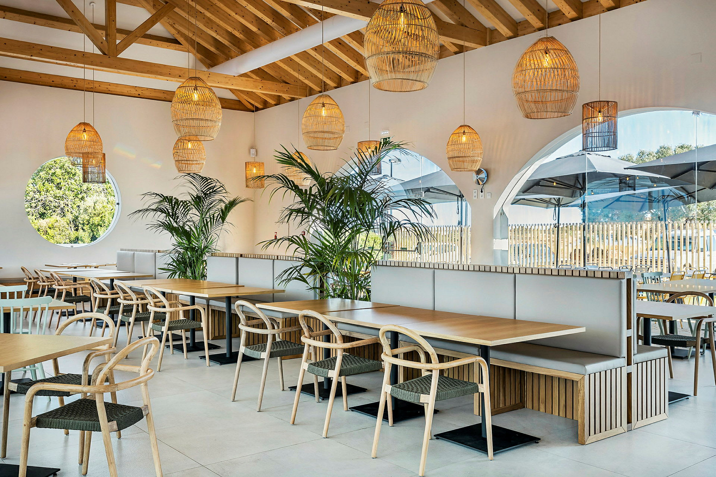 En moderne restaurant med træborde, stole og grønne planter. (AI-genereret tekst)