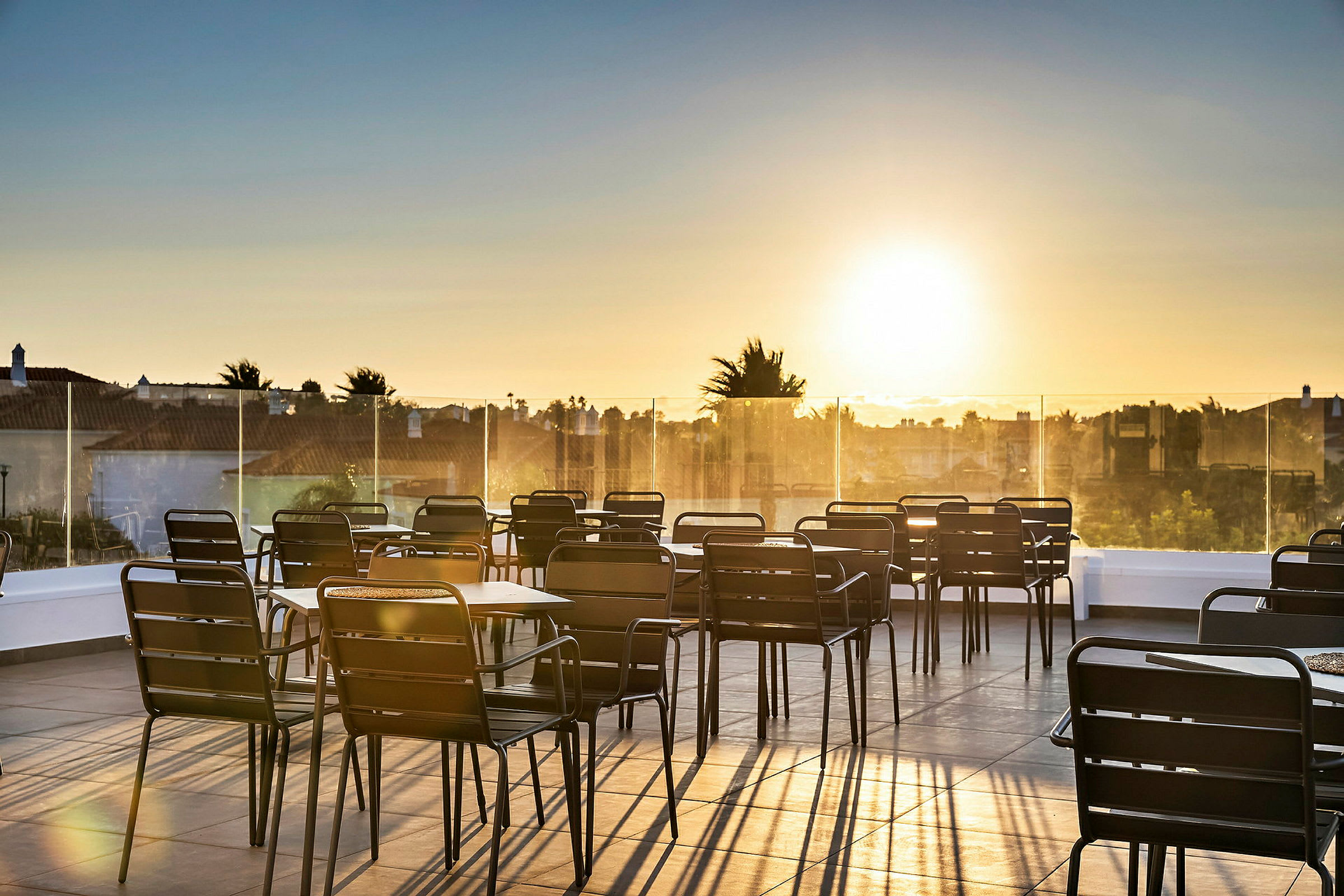 En terrasse med borde og stole ved solnedgang. (AI-genereret tekst)