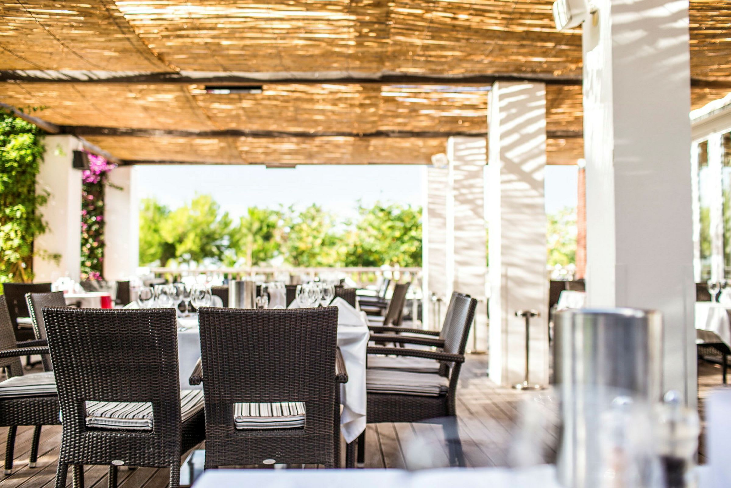 En udendørsrestaurant med dækkede borde under en pergola. (AI-genereret tekst)