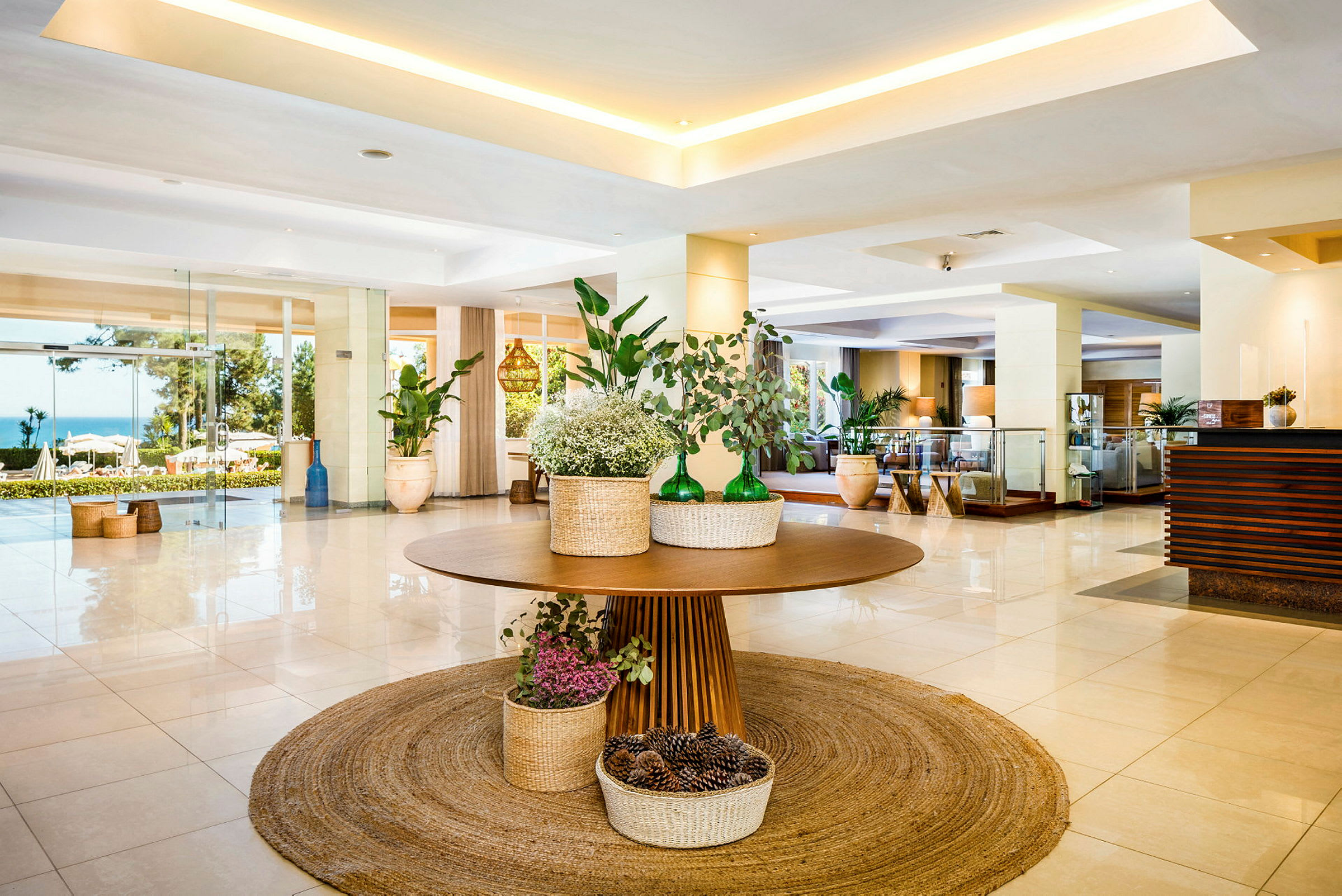 Hotellets lobby med et dekoreret bord med planter og kurve på et rundt tæppe. (AI-genereret tekst)