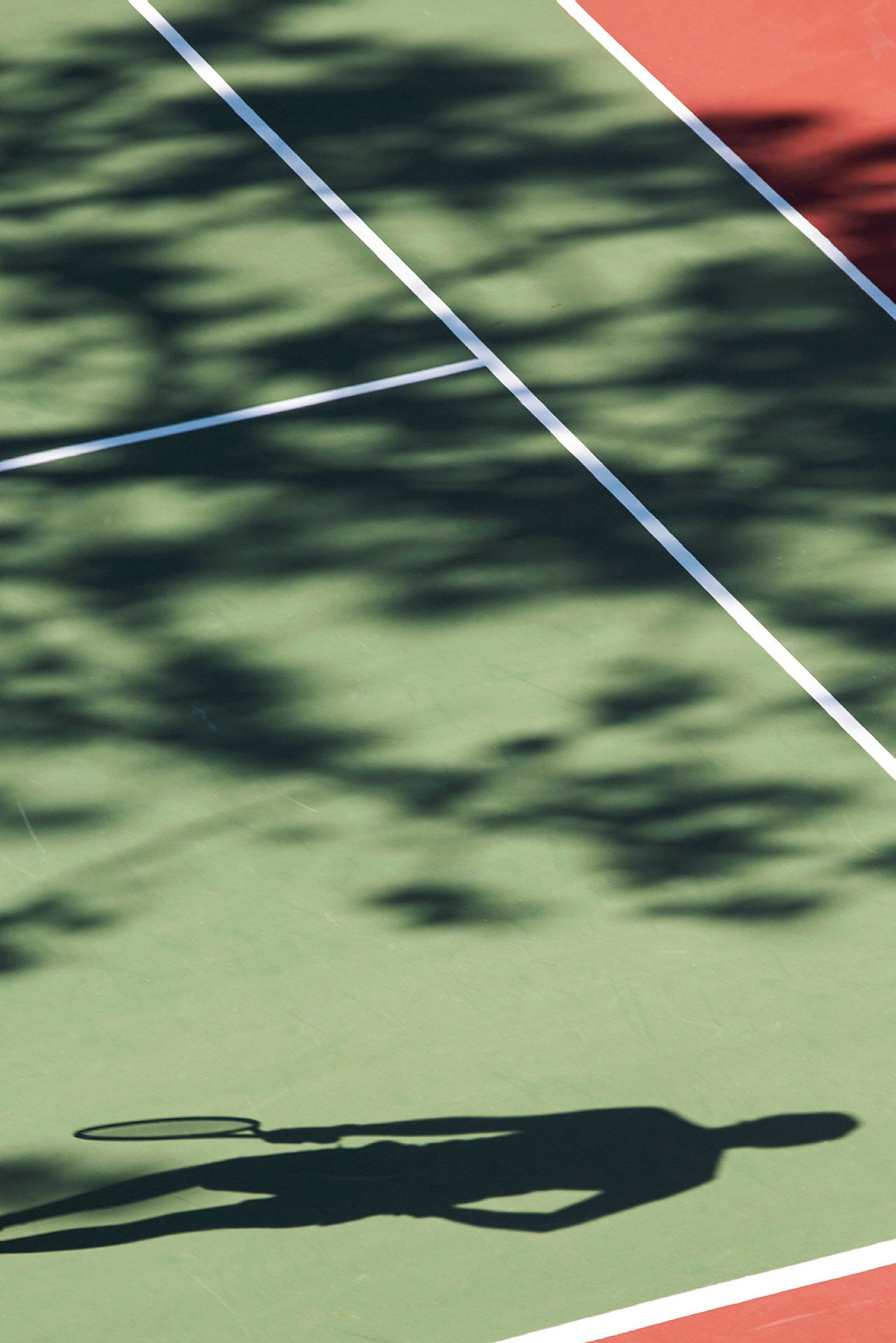 Skygge af en person med tennisracket på en tennisbane. (AI-genereret tekst)