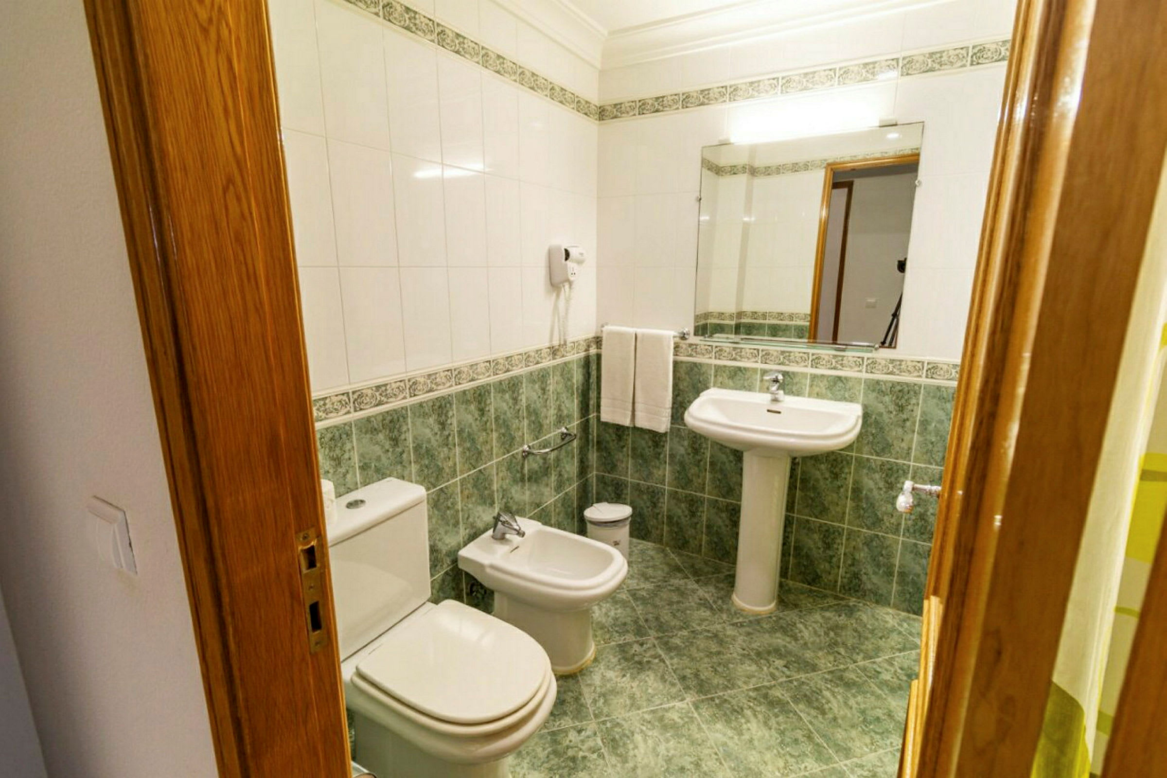 Et badeværelse med toilet, bidet og håndvask. (AI-genereret tekst)