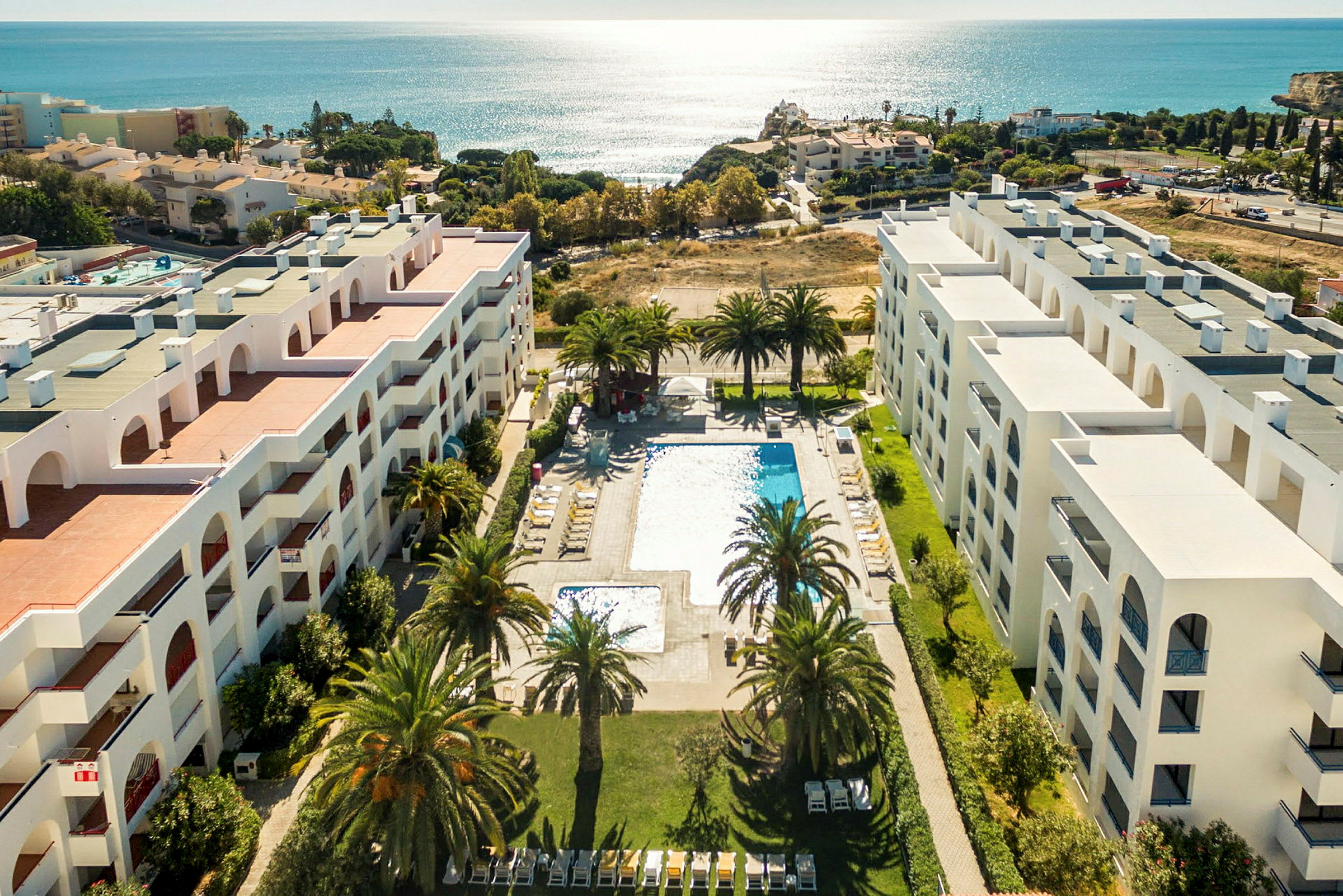 Luftfoto af hotel med poolområde og udsigt over havet. (AI-genereret tekst)