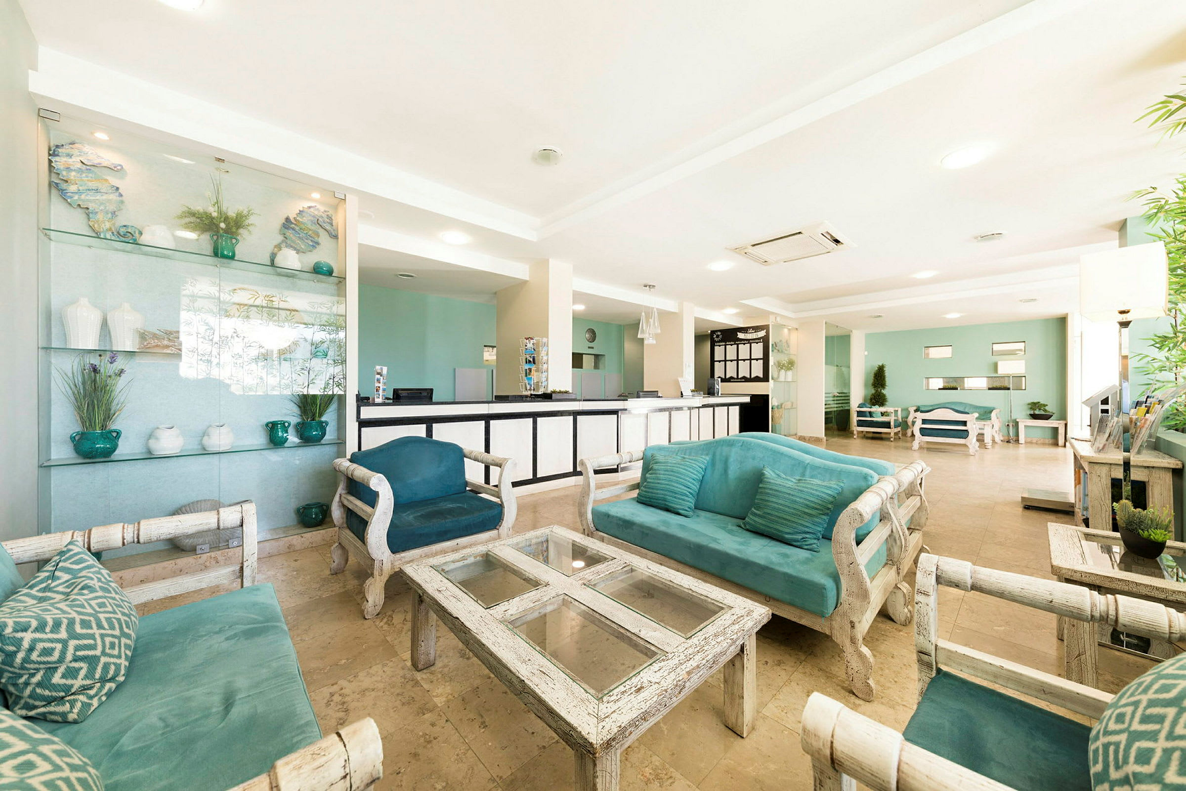 Lyse hotellobby med turkis sofaer, glasbord og receptionsdisk. (AI-genereret tekst)
