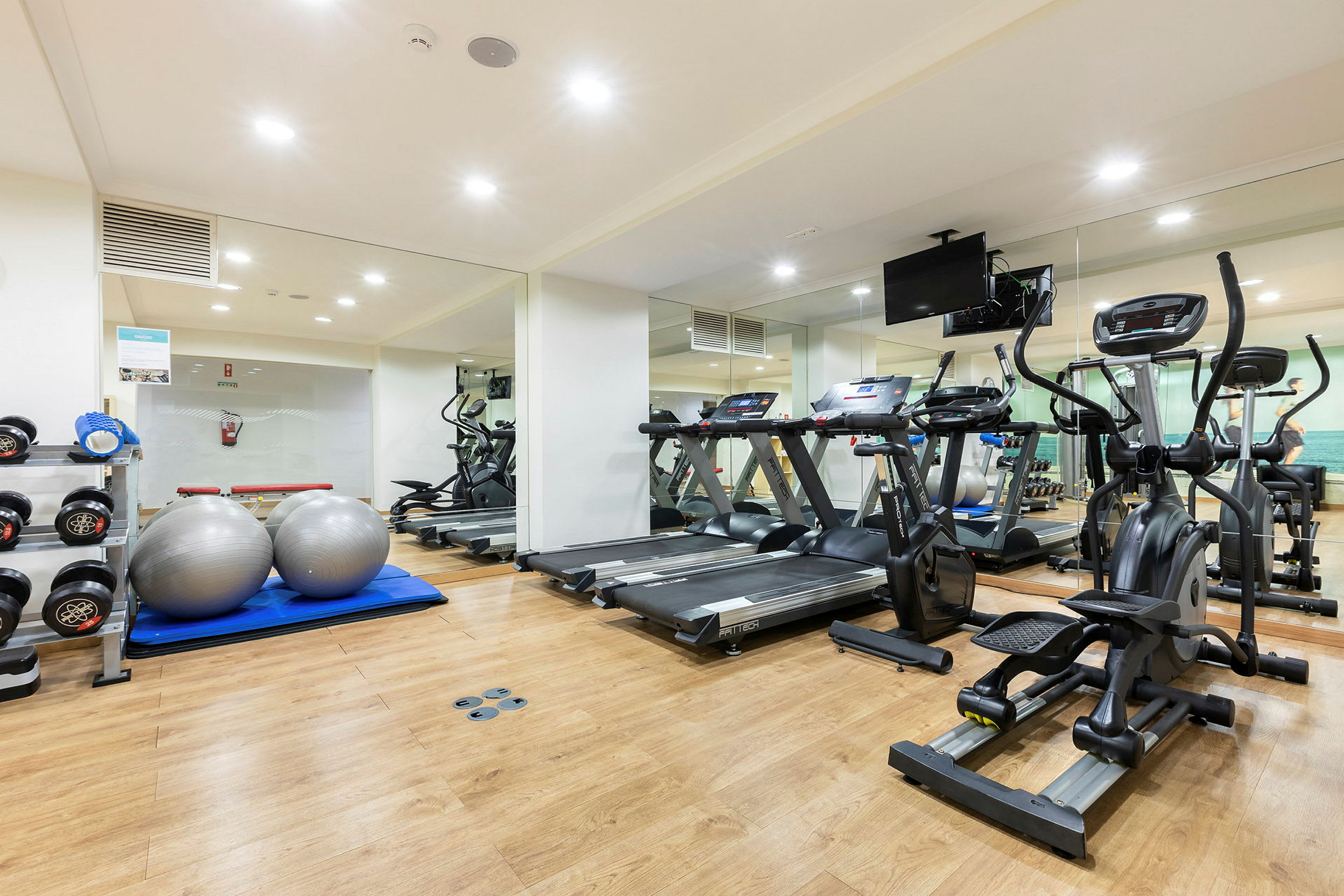 Et fitnesscenter med træningsmaskiner, håndvægte og pilatesbolde. (AI-genereret tekst)