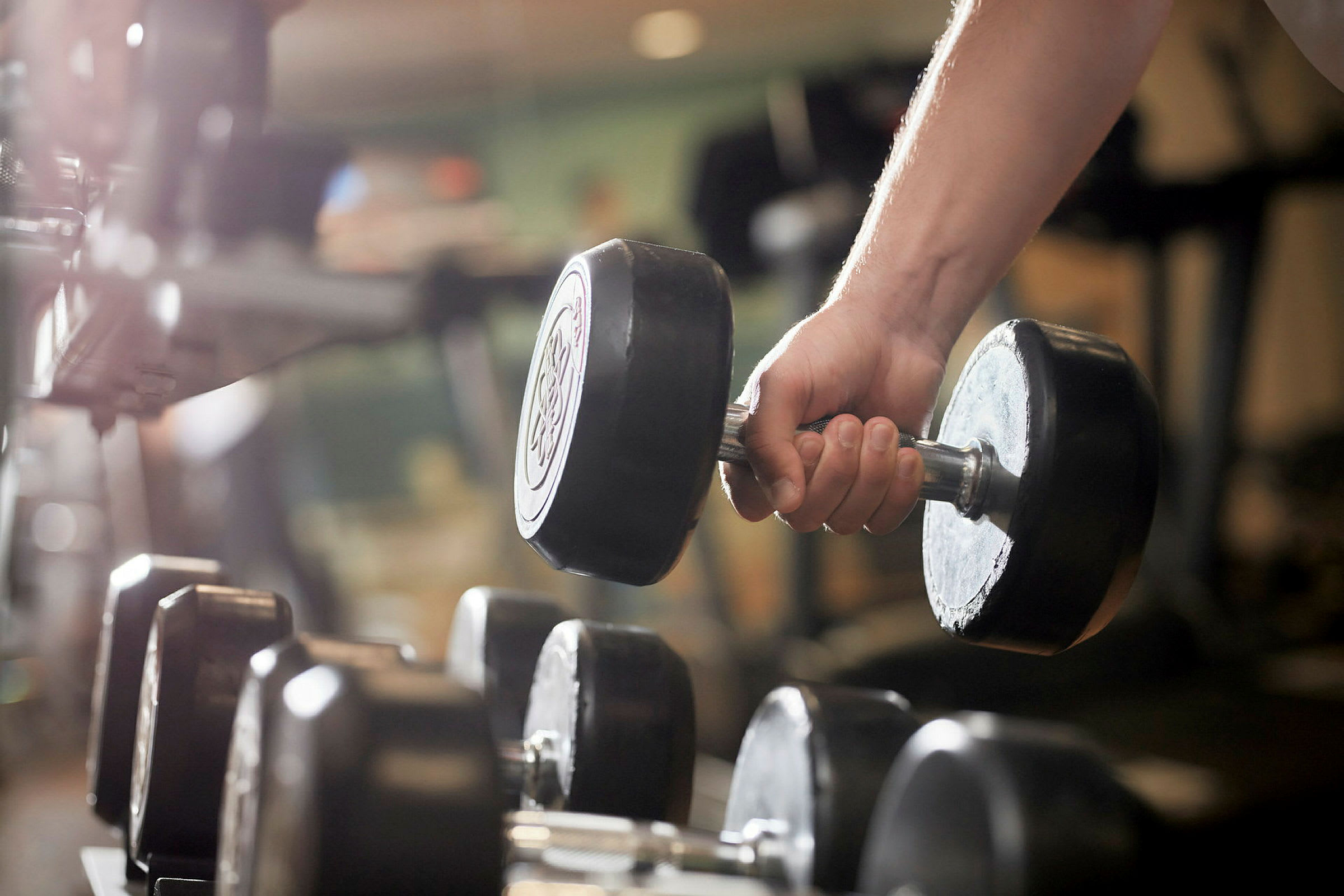 En hånd holder en håndvægt i et fitnesscenter. (AI-genereret tekst)