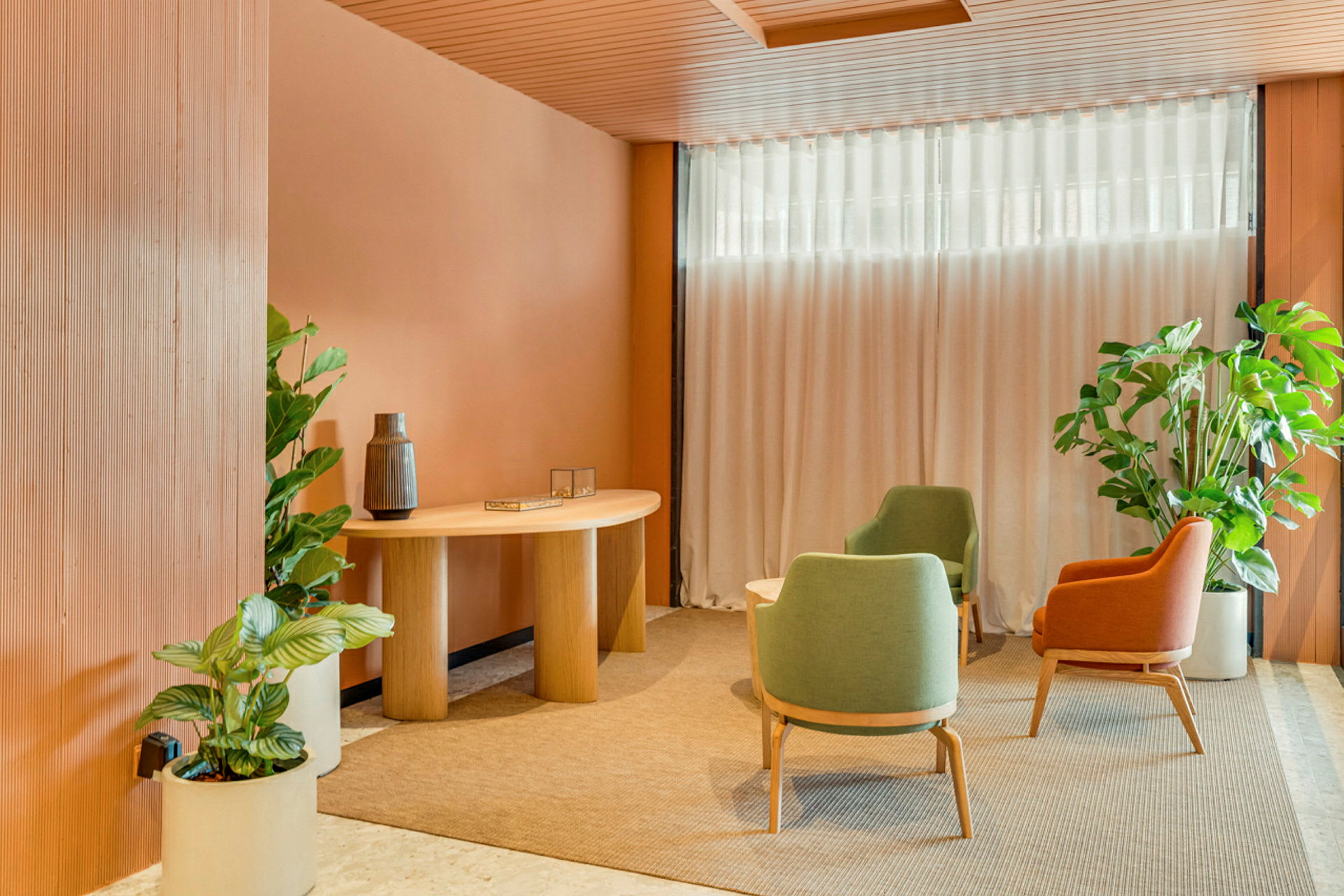 Et indbydende rum med moderne interiør, forsynet med farverige lænestole, et træbord og omgivet af dekorative planter. (AI-genereret tekst)