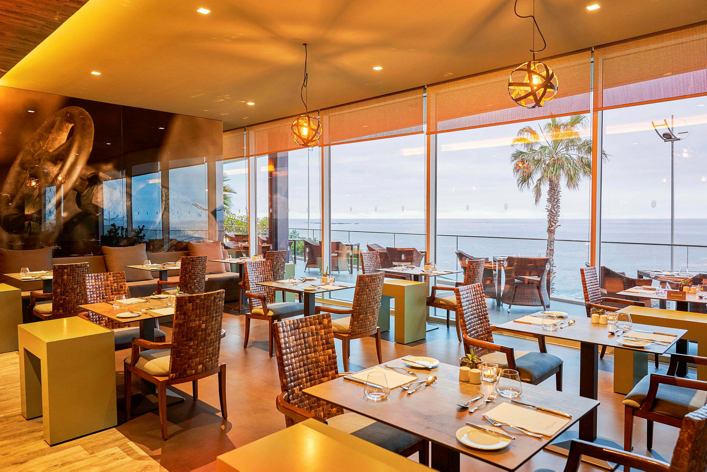 Restaurant med siddepladser og store vinduer mod havet. (AI-genereret tekst)