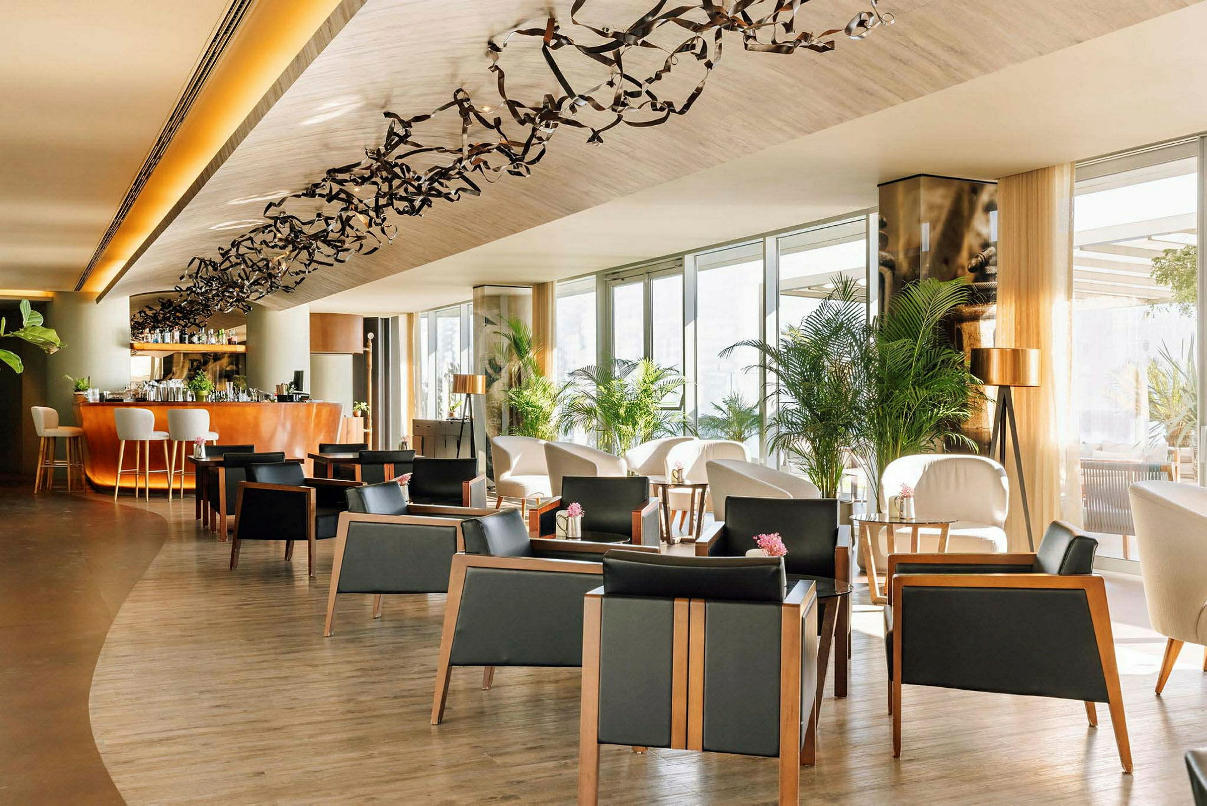 Et elegant loungeområde med stole, borde og dekorative planter. En bar i baggrunden. (AI-genereret tekst)