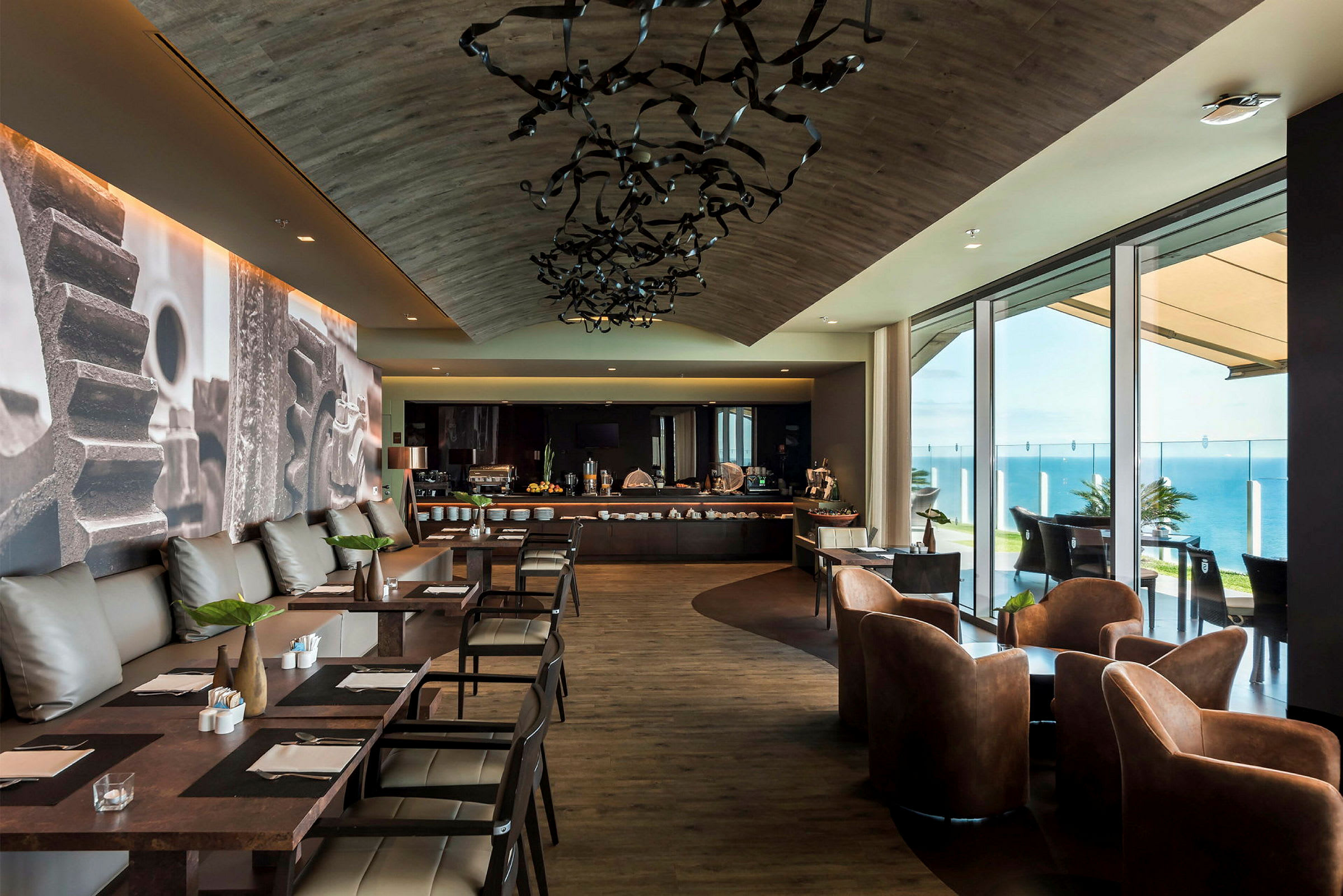 En moderne restaurant med siddepladser og en buffetbord ved vinduer med udsigt over havet. (AI-genereret tekst)