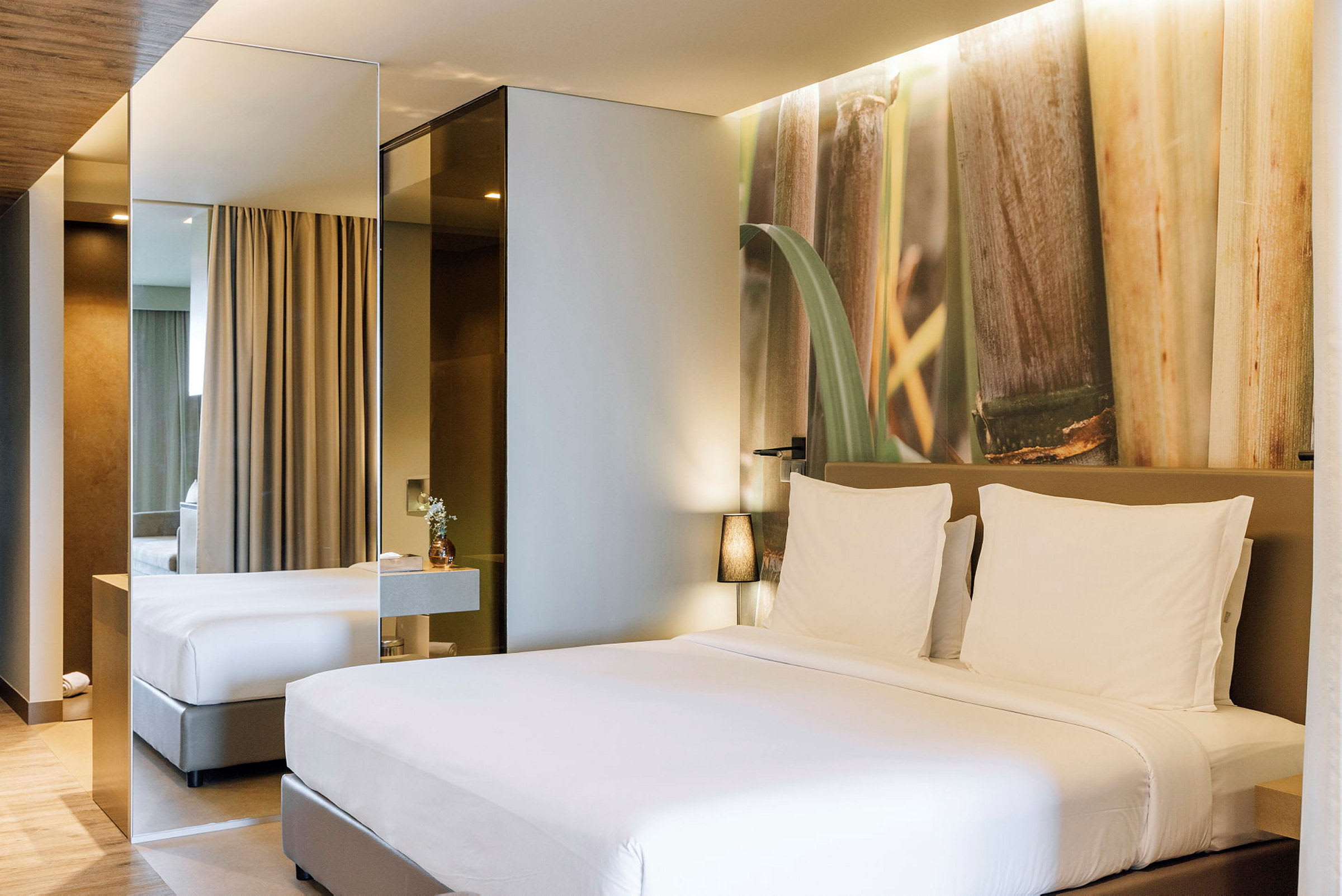 Et moderne hotelværelse med en stor seng med hvidt sengetøj og en dekorativ væg med naturmotiv. (AI-genereret tekst)