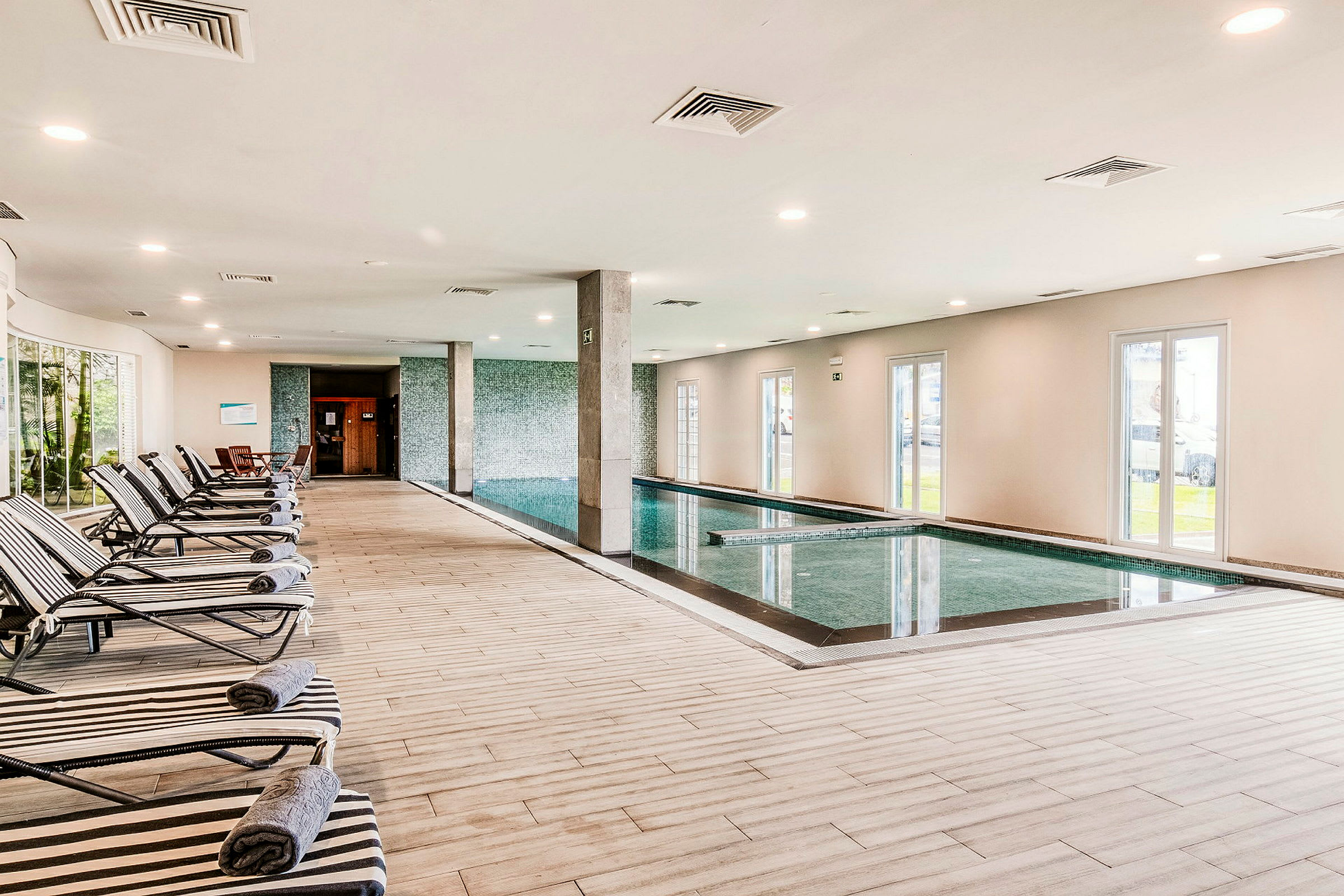 Indendørs swimmingpool med afslapningsområde og liggestole. (AI-genereret tekst)