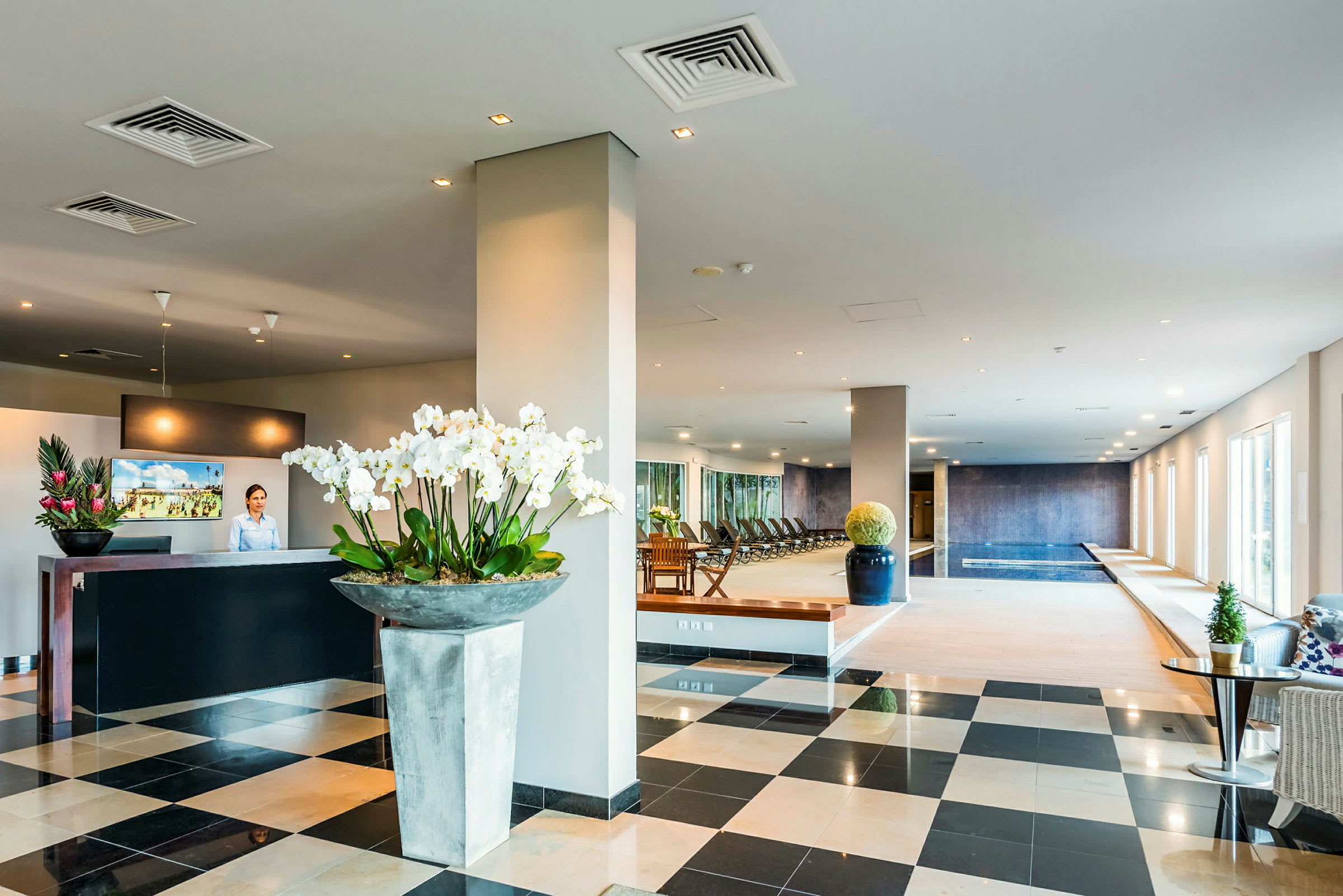 Et hotelområde med reception og spaafdeling, herunder pool og siddekroge. (AI-genereret tekst)