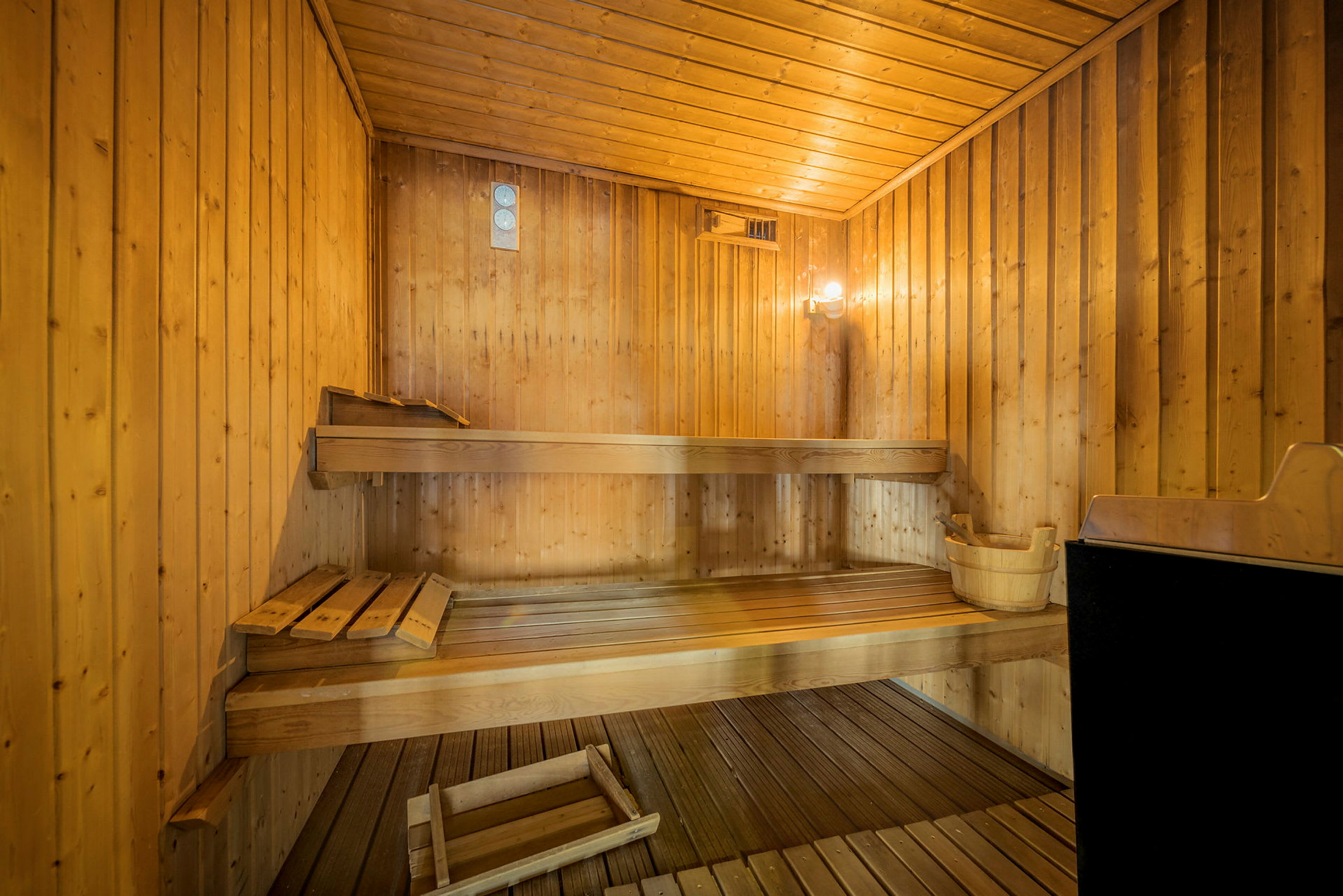 En traditionel sauna med træpaneler, træbænke og en saunaovn. (AI-genereret tekst)