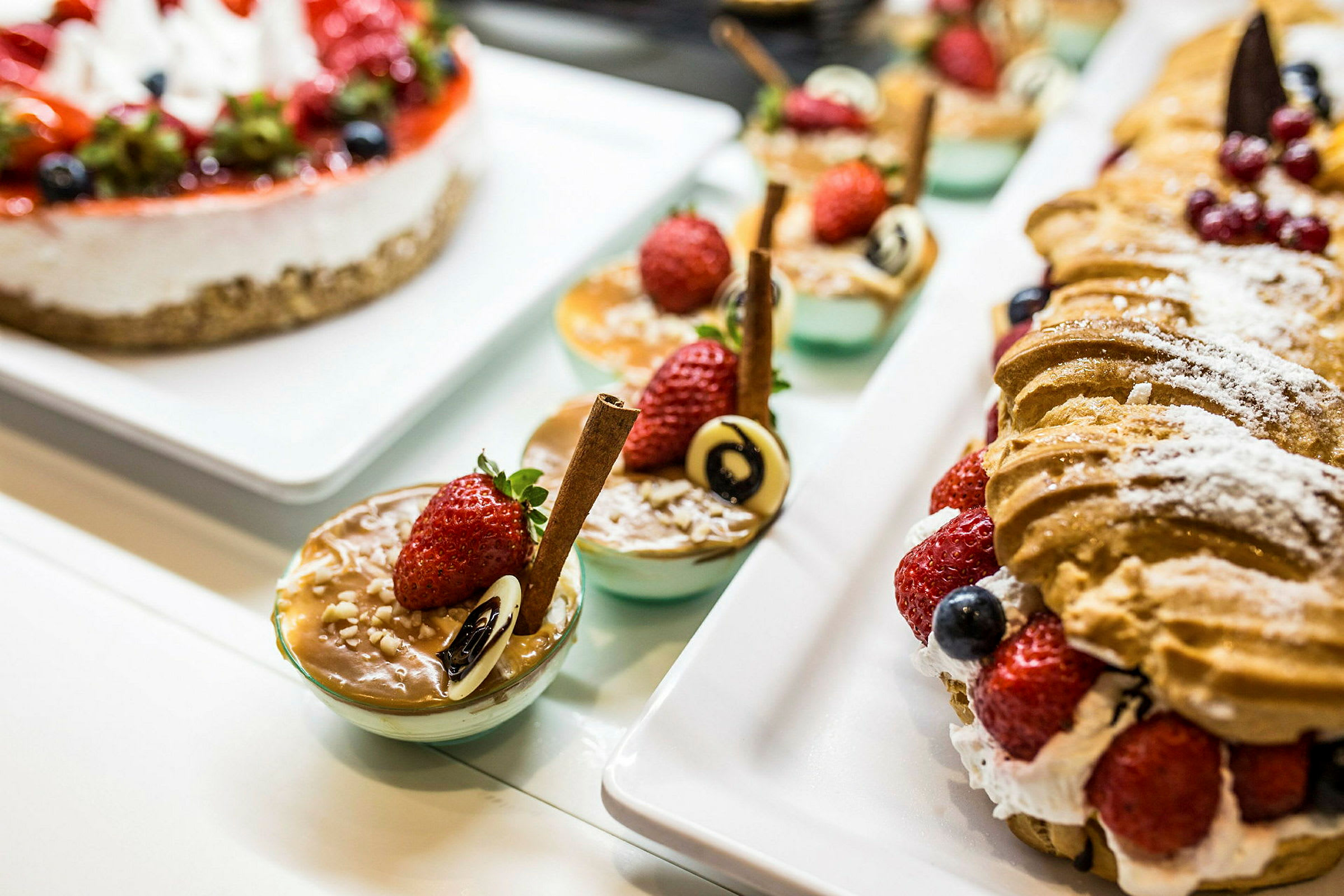Et udvalg af desserter, inklusive bagværk og små portionsanretninger med pynt som jordbær og chokolade. (AI-genereret tekst)