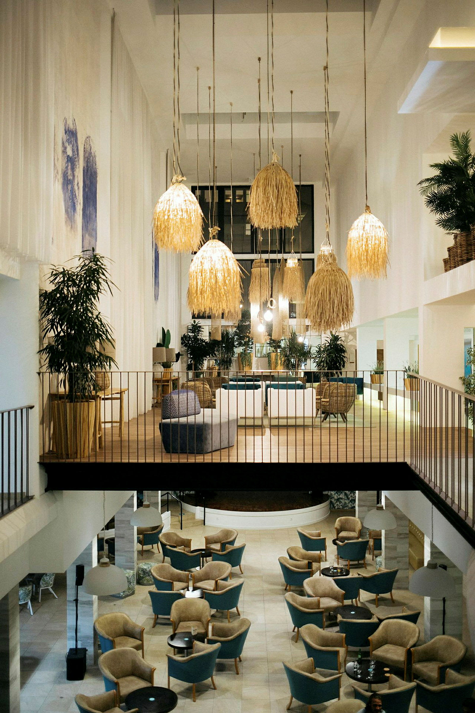 Interiøret i et rummeligt og elegant hotelområde med siddegrupper og store hængende lamper. (AI-genereret tekst)