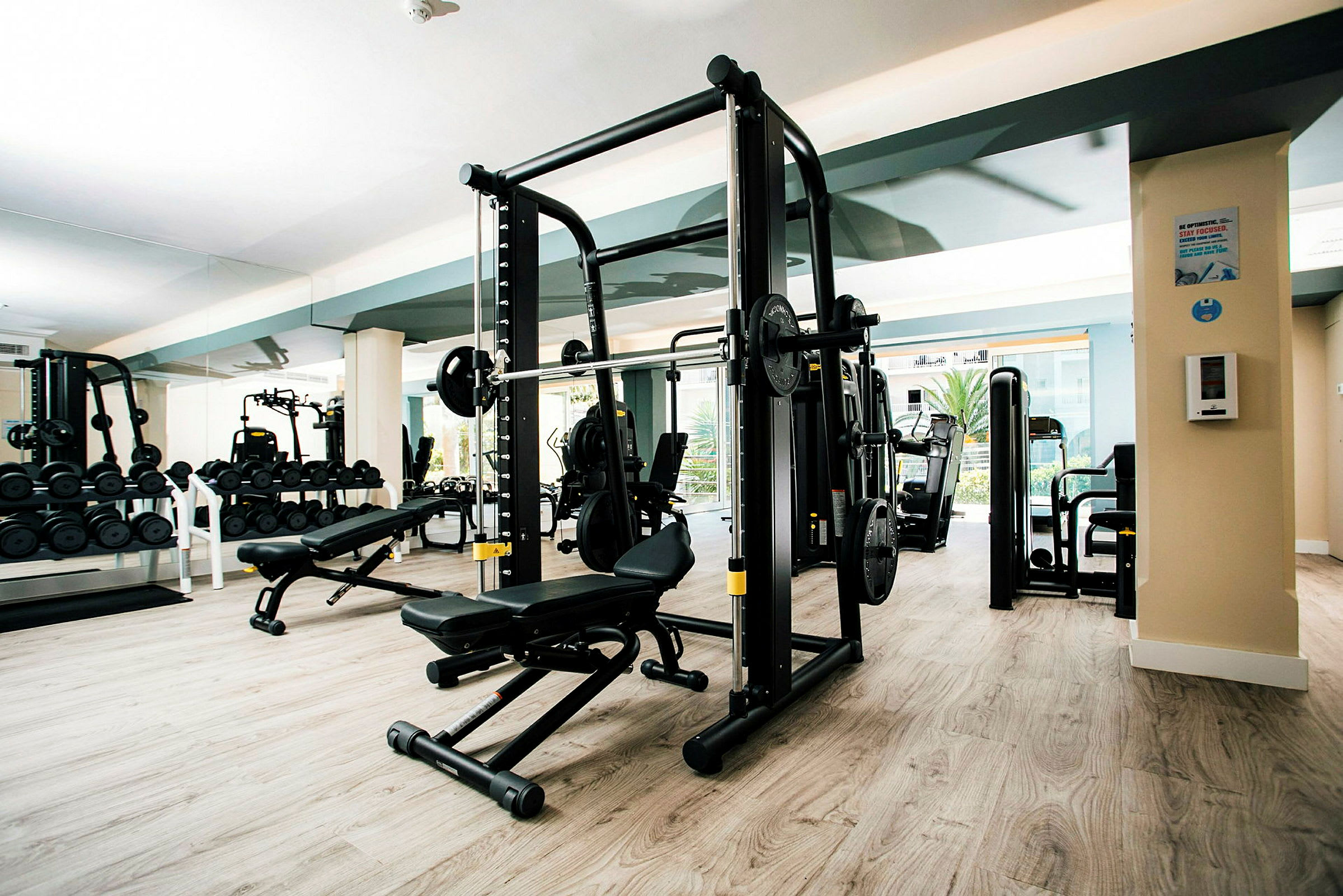 Træningslokale med fitnessudstyr og spejlvæg. (AI-genereret tekst)