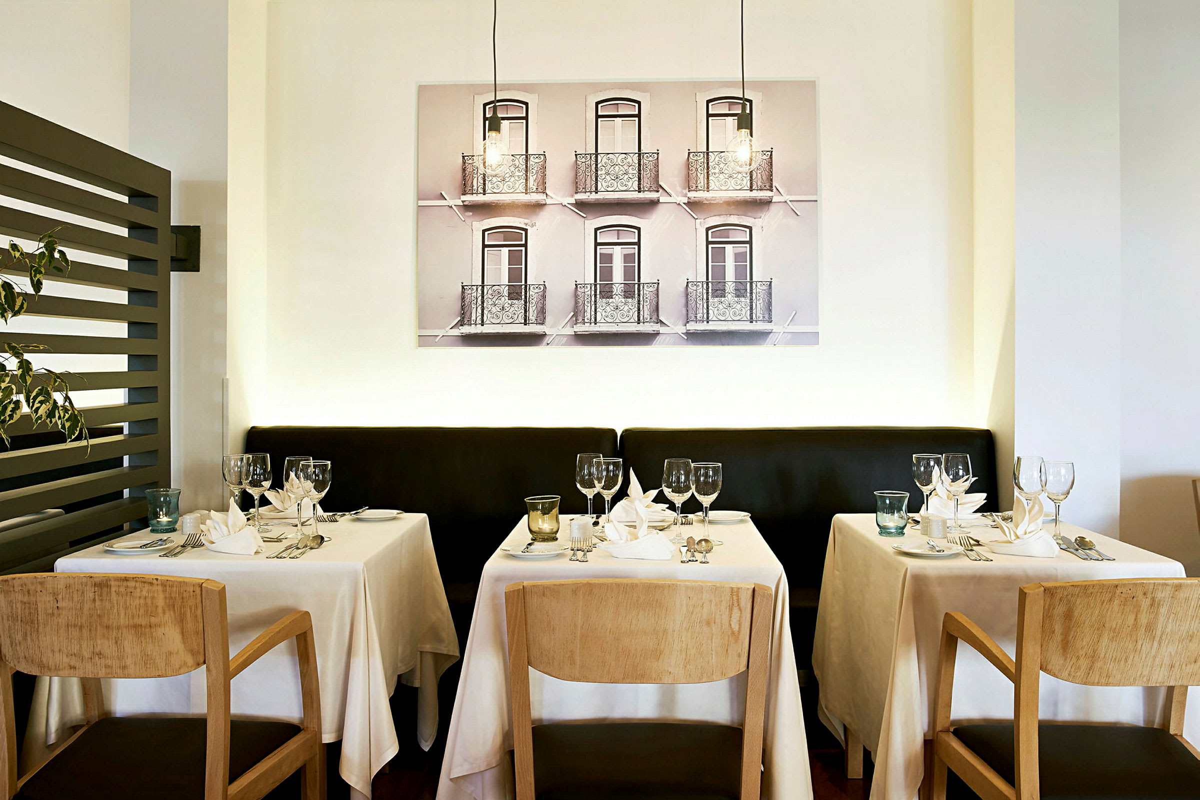 Restaurant med dækkede borde foran en væg med fotokunst. (AI-genereret tekst)
