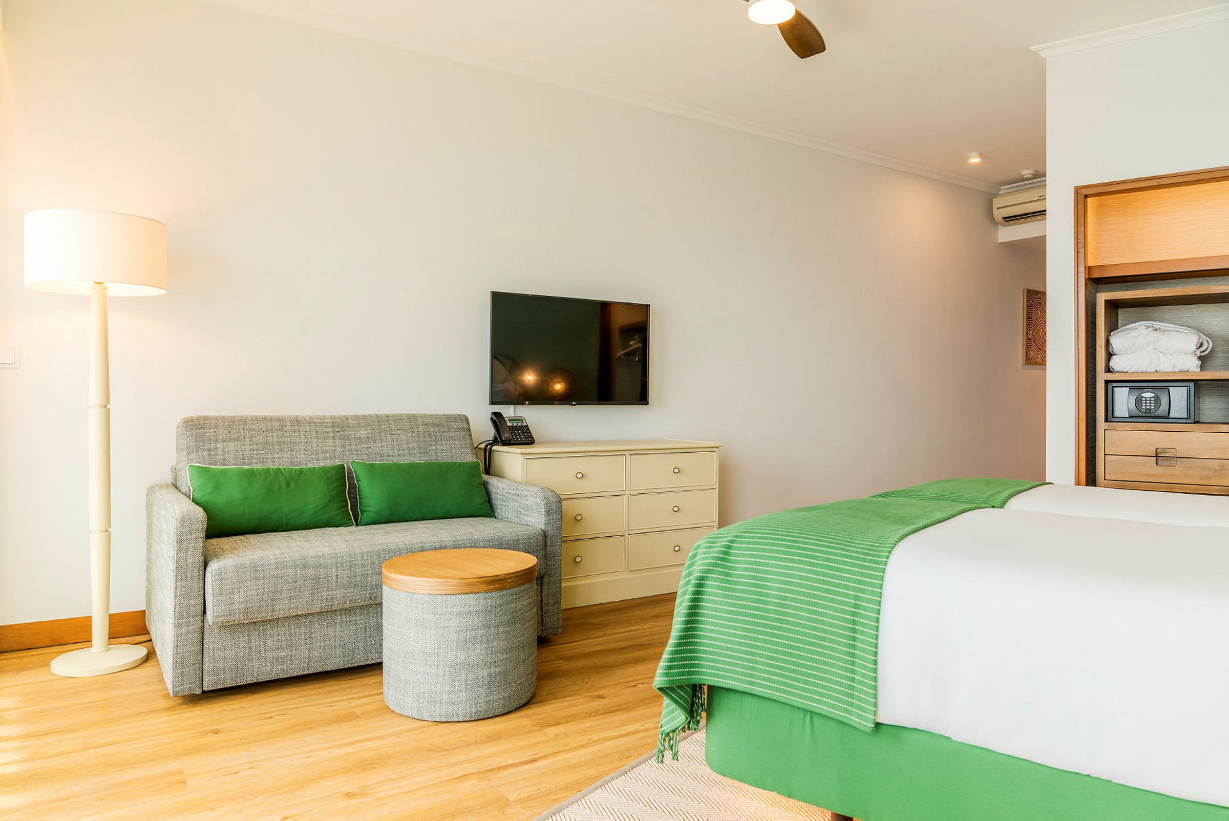 Et hotelværelse med en sofa, et lille bord, en seng og et TV på væggen. (AI-genereret tekst)