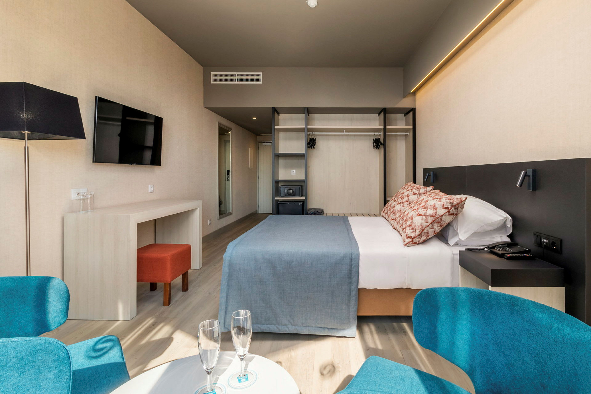 Et hotelværelse med dobbeltseng, skrivebord, stol og garderobe. (AI-genereret tekst)