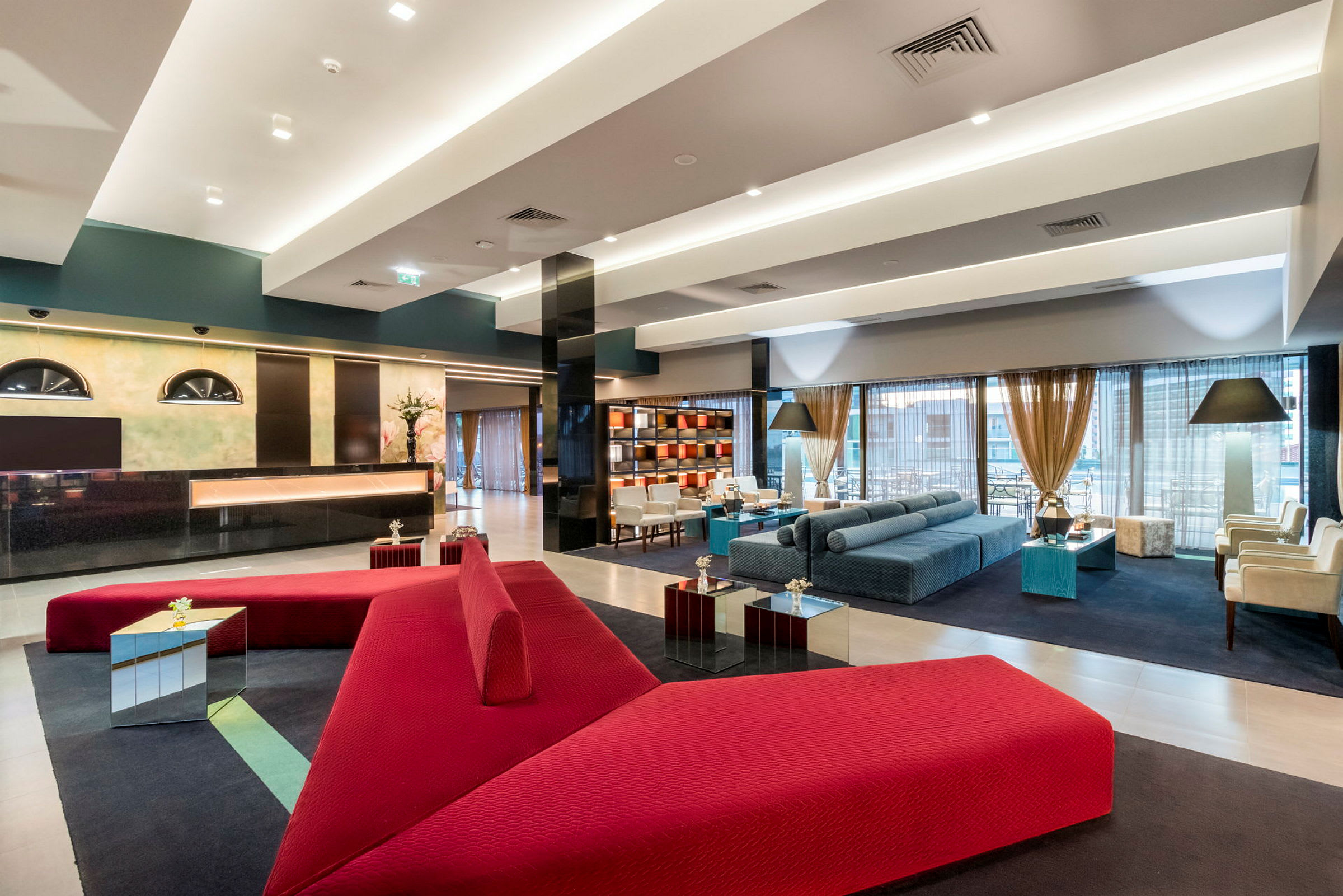 Moderne hotellobby med røde og blå møbler. (AI-genereret tekst)
