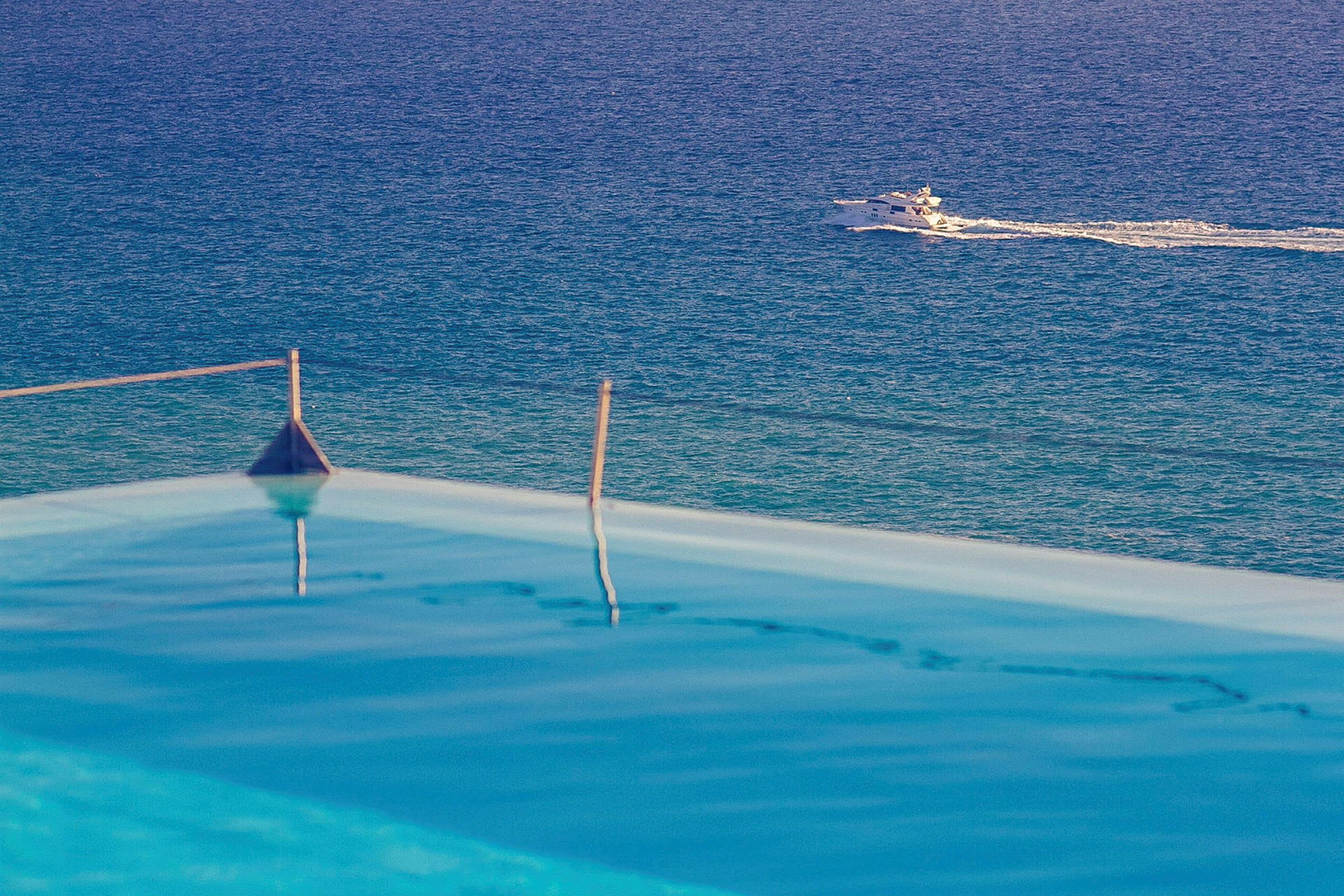 Infinitypool med udsigt over havet og en motorbåd, der passerer i baggrunden. (AI-genereret tekst)