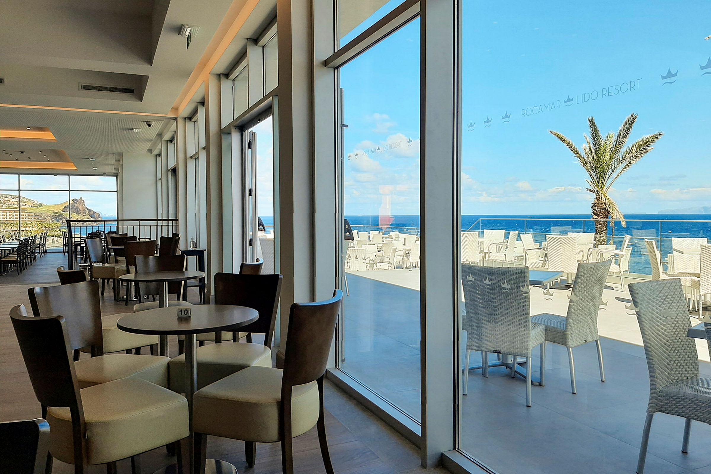 Billede af en restaurant med siddepladser indendørs og terrasse med havudsigt. (AI-genereret tekst)