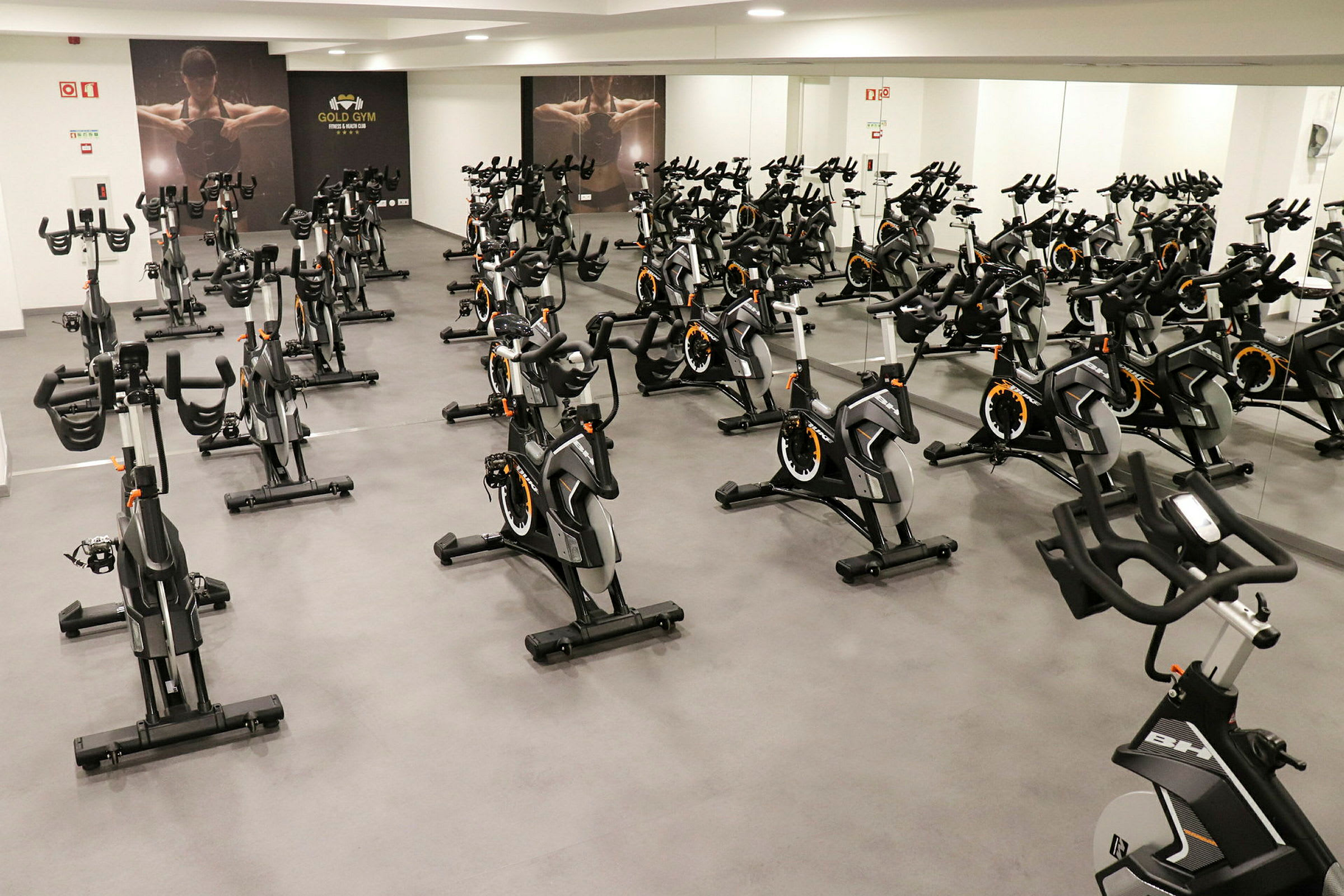 Et fitnesscenter med flere motionscykler i et rum med spejlvægge. (AI-genereret tekst)