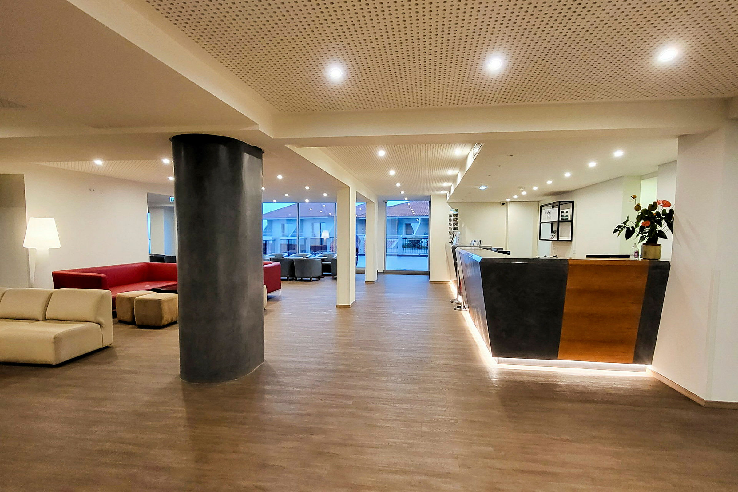 Hotellets lobby med siddegrupper, reception og store vinduer. (AI-genereret tekst)