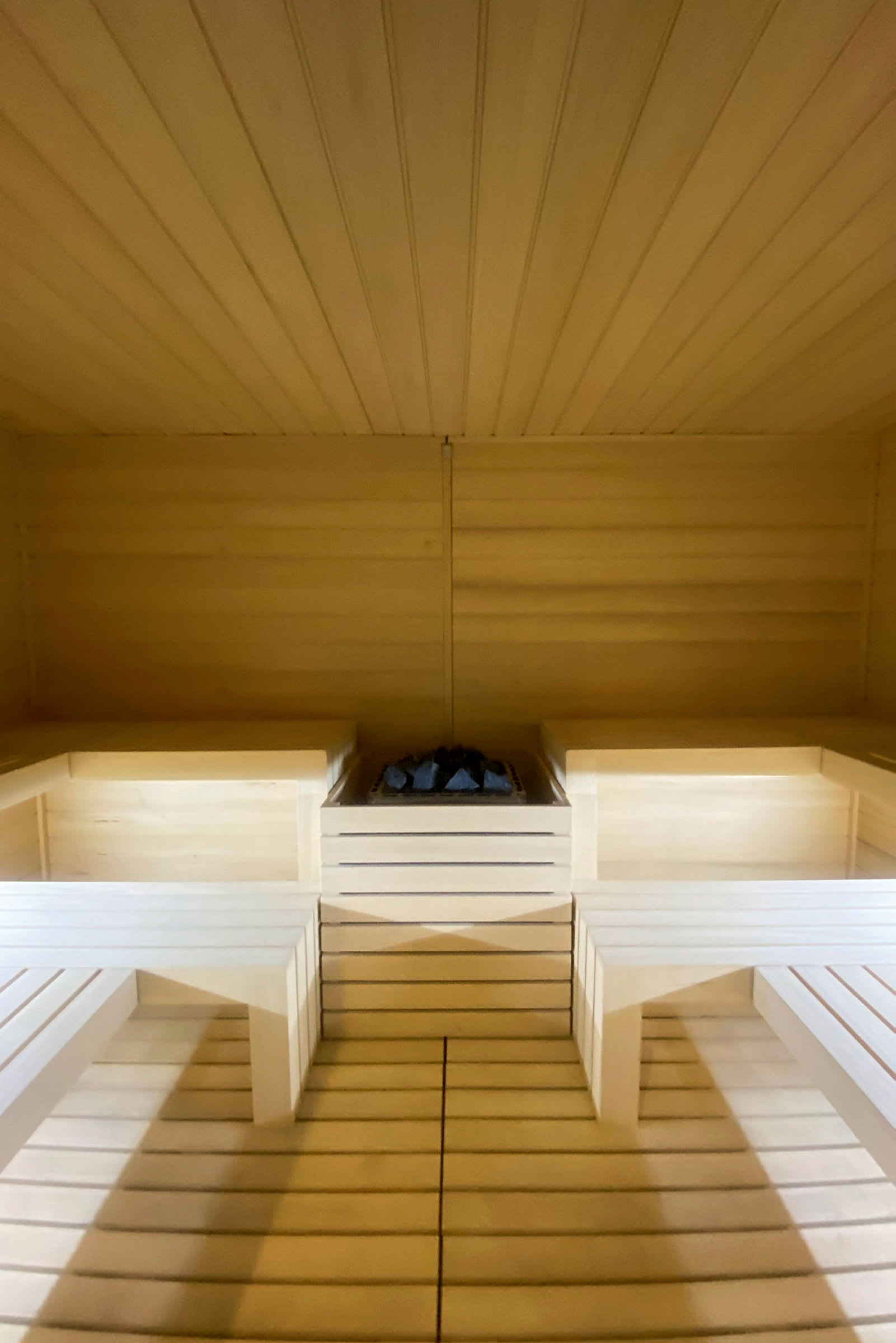 Billede af en træindrettet sauna med en saunaovn i midten. (AI-genereret tekst)