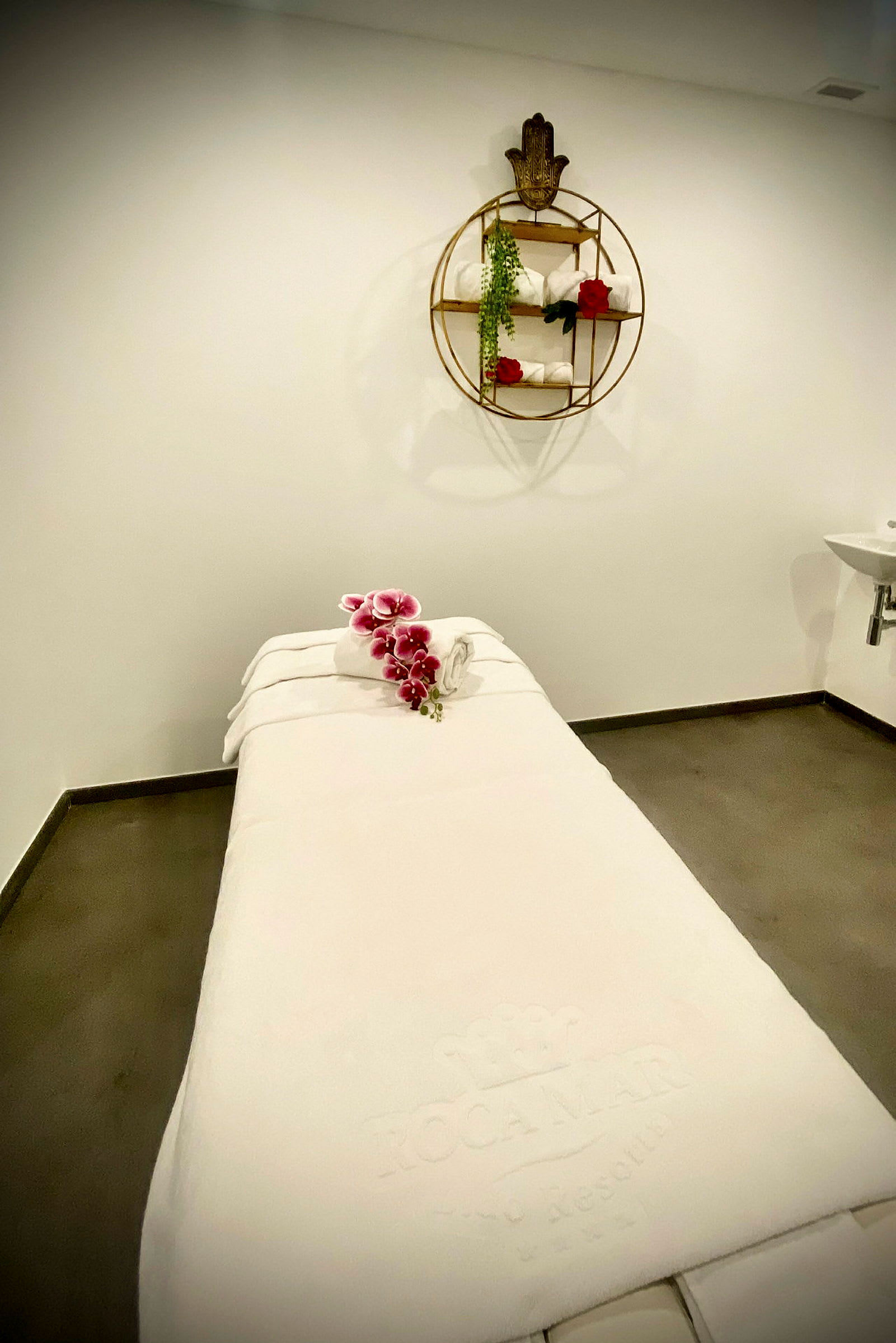 En massagebænk i et spa-rum med håndklæder og blomster. (AI-genereret tekst)