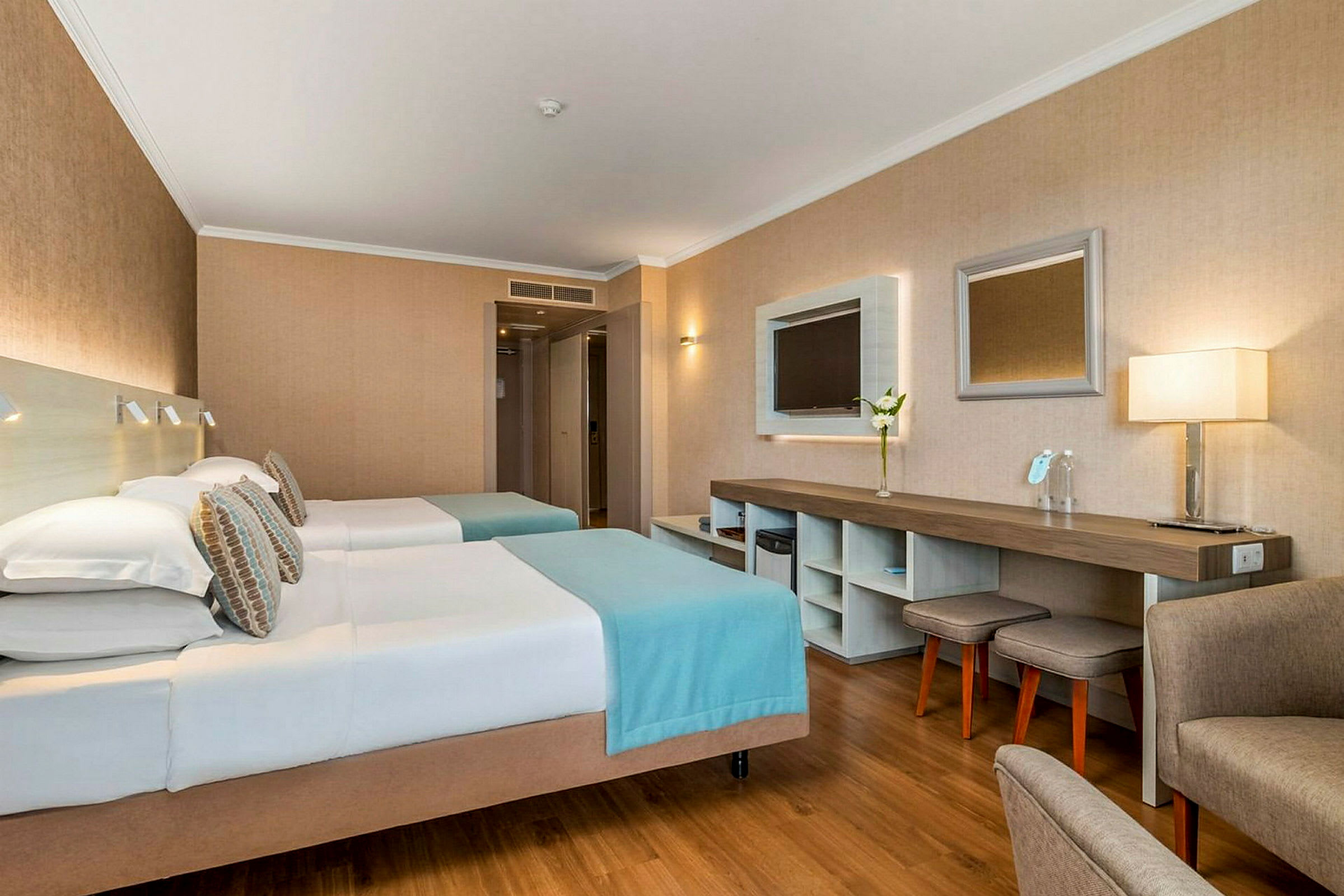 Hotelværelse med to enkeltsenge, arbejdsområde og sidde møbler. (AI-genereret tekst)