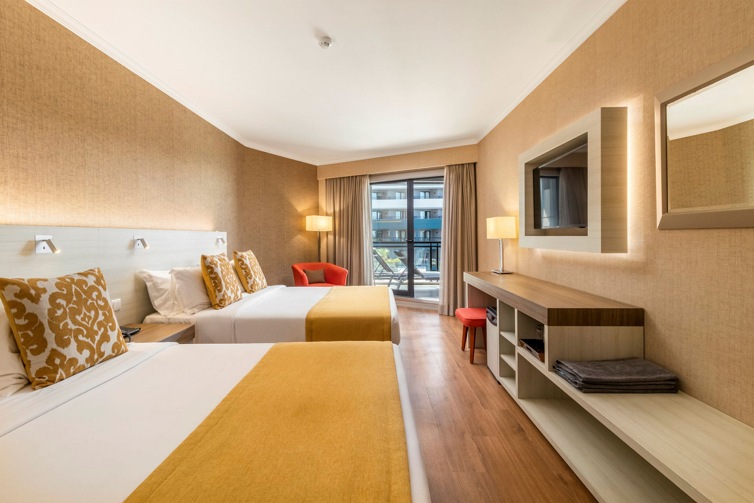 Hotelværelse med to senge, en lænestol og udsigt til balkon. (AI-genereret tekst)