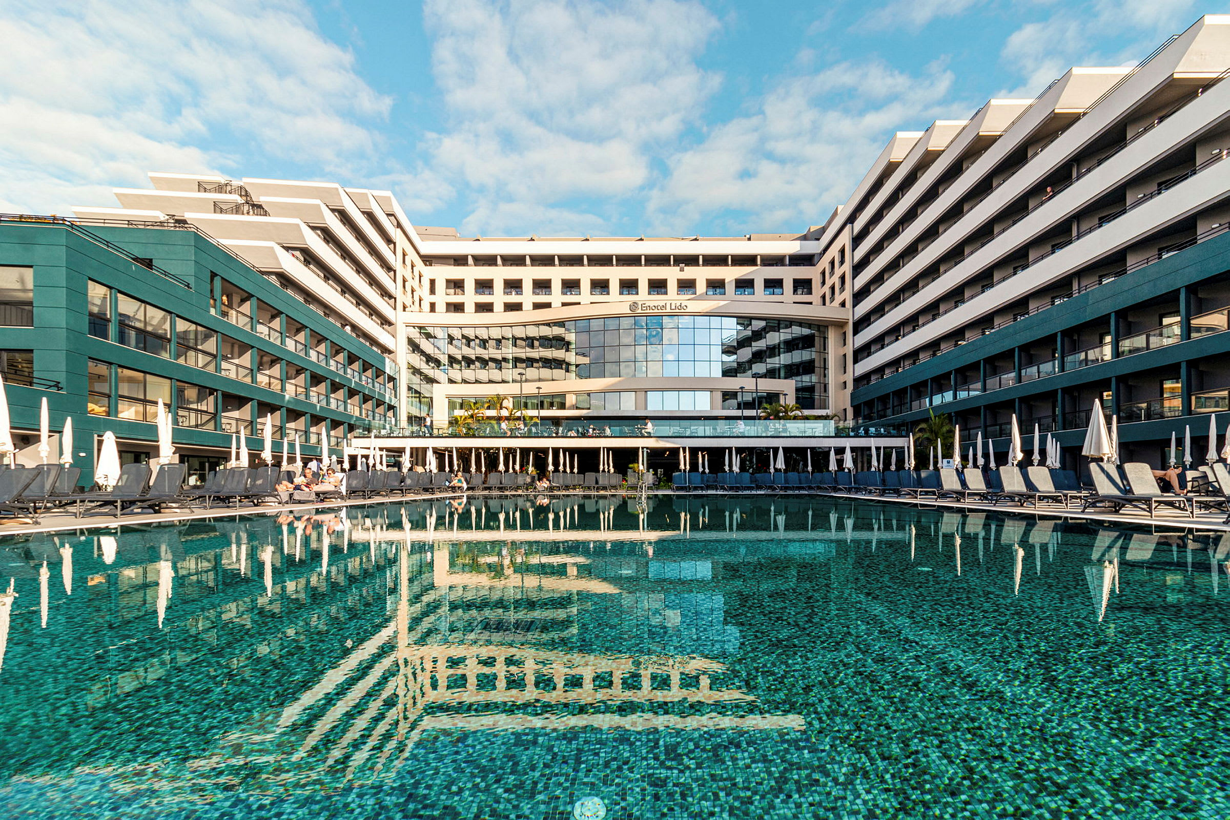 Hotel med pool og liggestole udendørs. (AI-genereret tekst)
