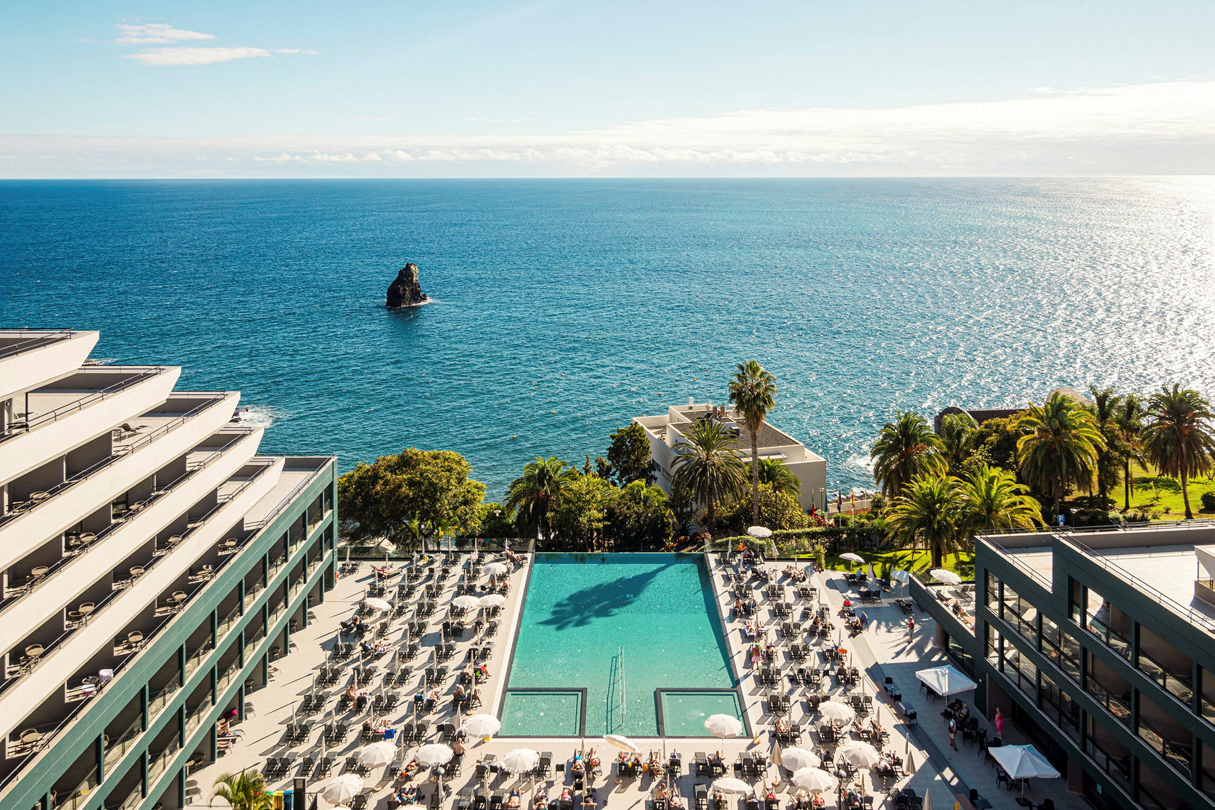 Hotel ved havet med en pool og liggestole. (AI-genereret tekst)