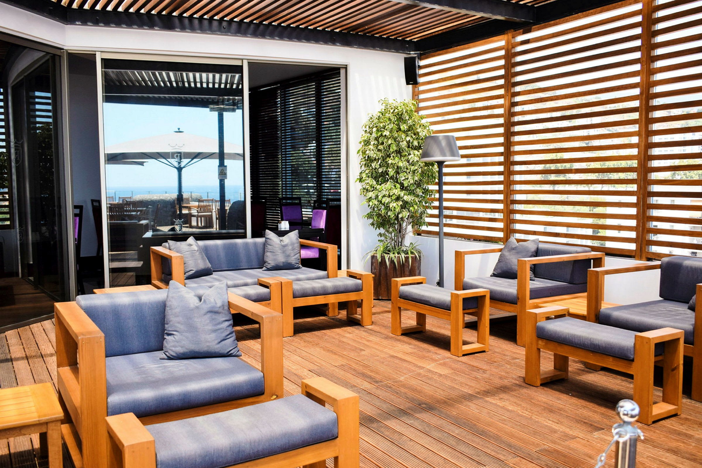 Terrasse med moderne træ- og tekstilmøbler, lamper og en potteplante. (AI-genereret tekst)
