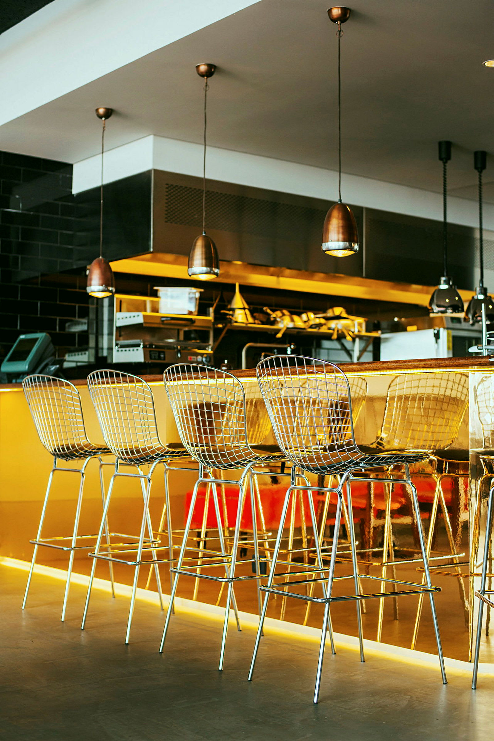 Barstole ved en guldfarvet bardisk i en moderne restaurantmiljø. (AI-genereret tekst)