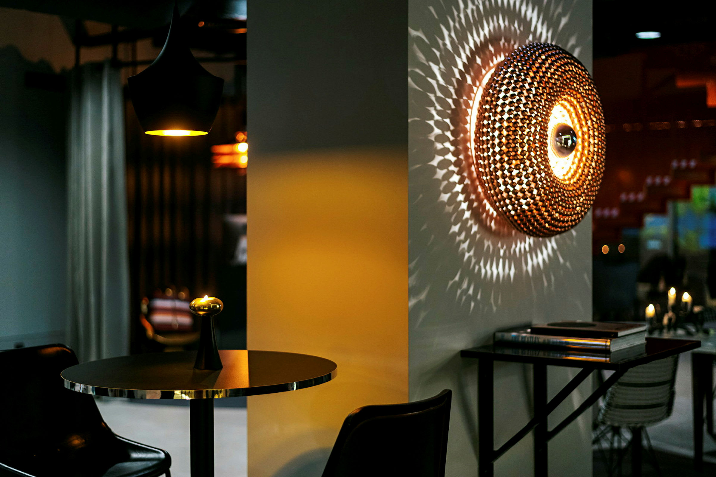Et interiør med et moderne bord med en lille lampe og en vægdekoration, der spreder lysmønstre. (AI-genereret tekst)