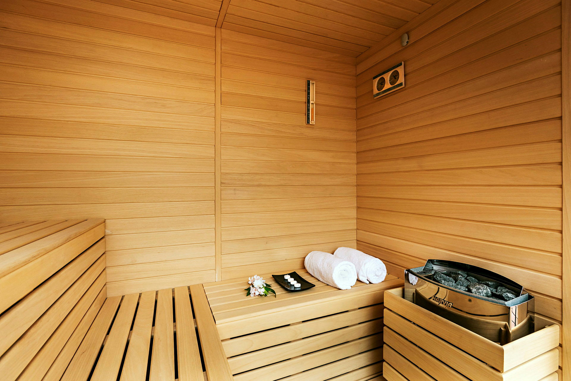 Sauna med træpaneler, to håndklæder og et fad med små lys. (AI-genereret tekst)