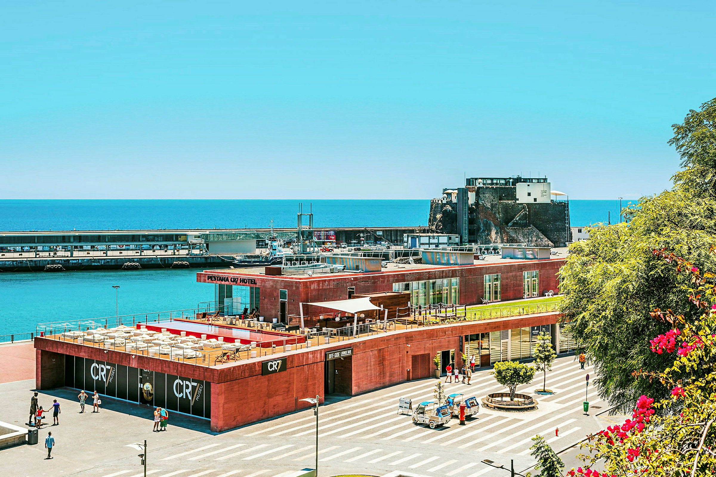 En hotelbygning nær havet med parkering og færgeterminal. (AI-genereret tekst)
