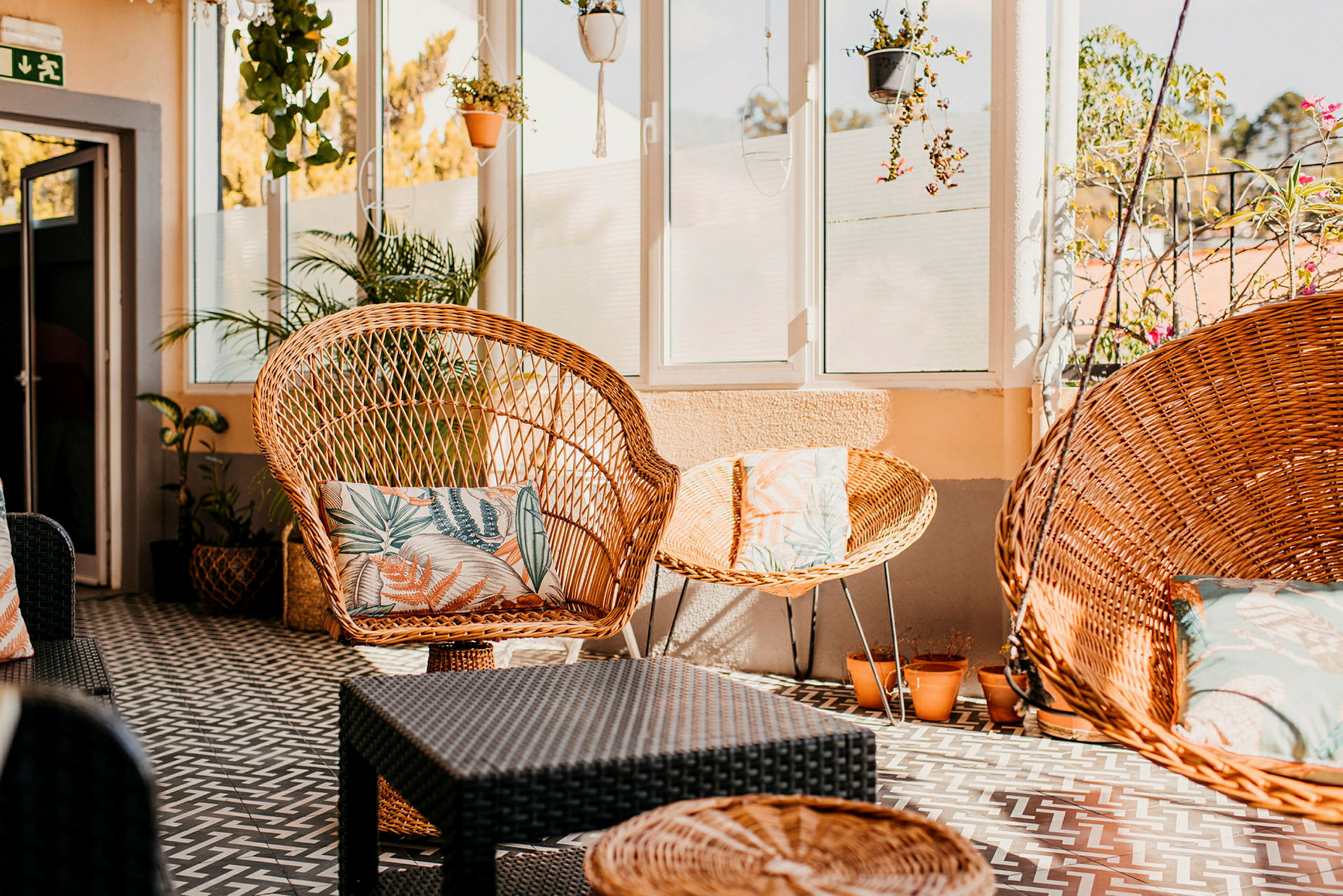 Billede af en terrasse med kurvemøbler og planter. (AI-genereret tekst)