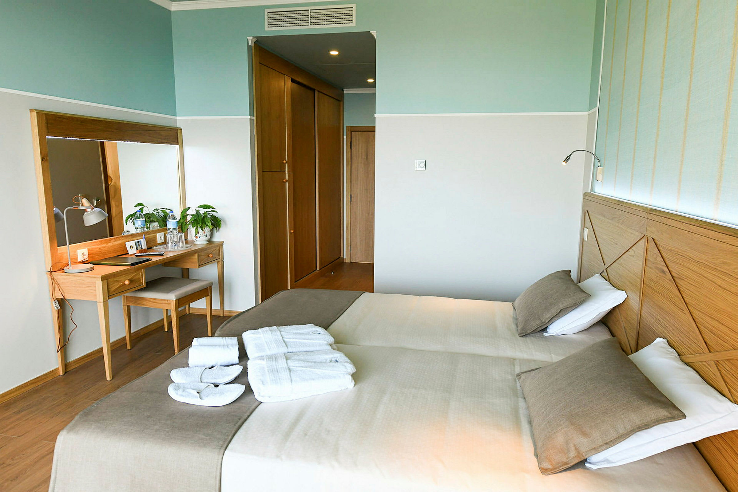 Hotelværelse med to enkeltsenge, et spejl og et skrivebord. (AI-genereret tekst)