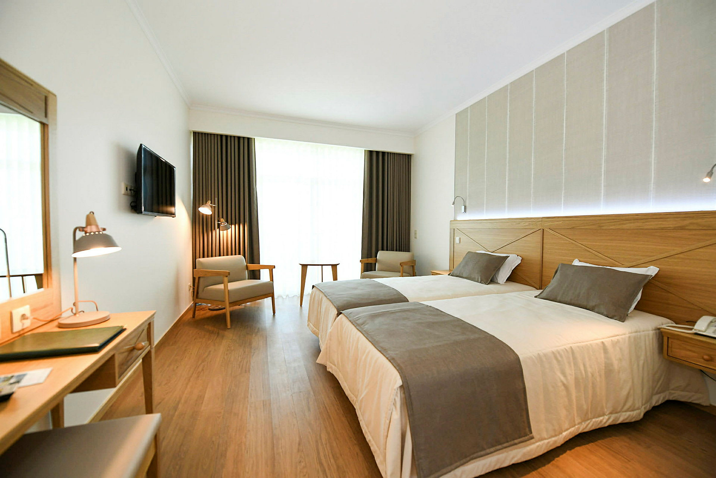 Hotelværelse med to enkeltsenge, skrivebord og siddepladser. (AI-genereret tekst)