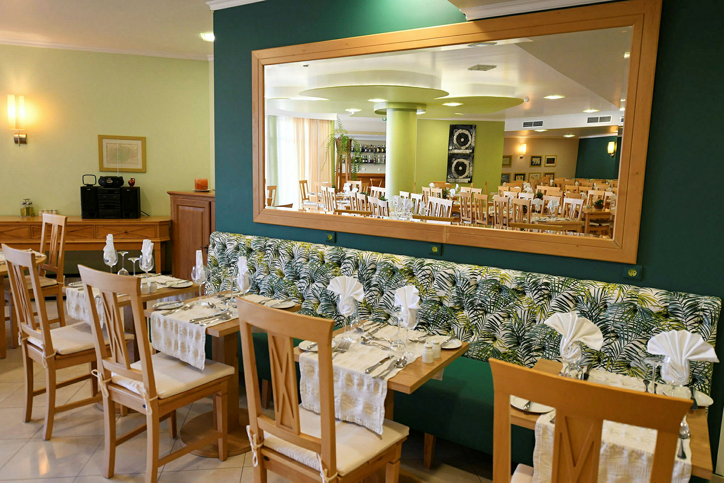 Restaurant med borde og stole samt spejl på væggen. (AI-genereret tekst)